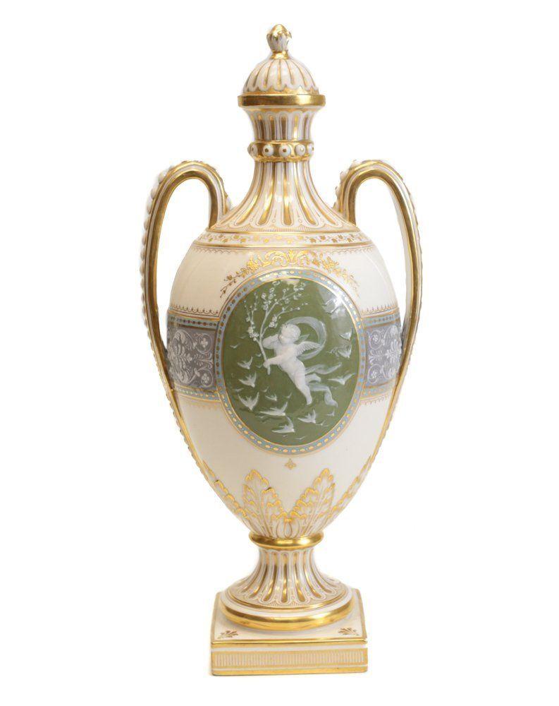 A Minton Pate Sur Pate teal and light grey porcelain vase and cover on an ivory color ground of twin handled baluster form, the central oval medallion depicting a young scantily clad maiden holding her dress, the reverse with a flying cherub with