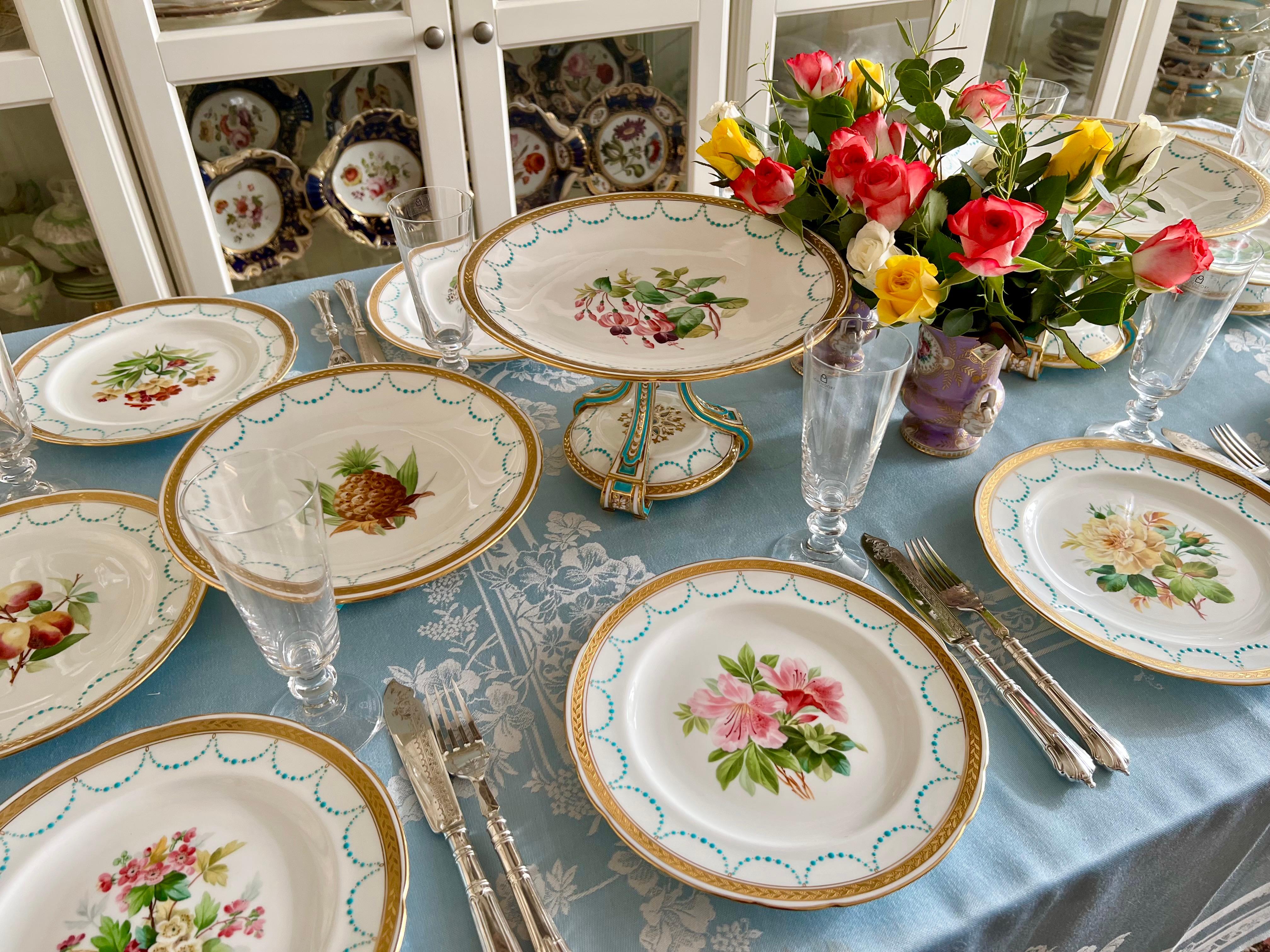This is a beautiful dessert service made by Minton in 1870. The service consists of two high comports, two low comports, and twelve plates. All items have a white ground with refined acid gilt border and turquoise festoons, and each item is painted