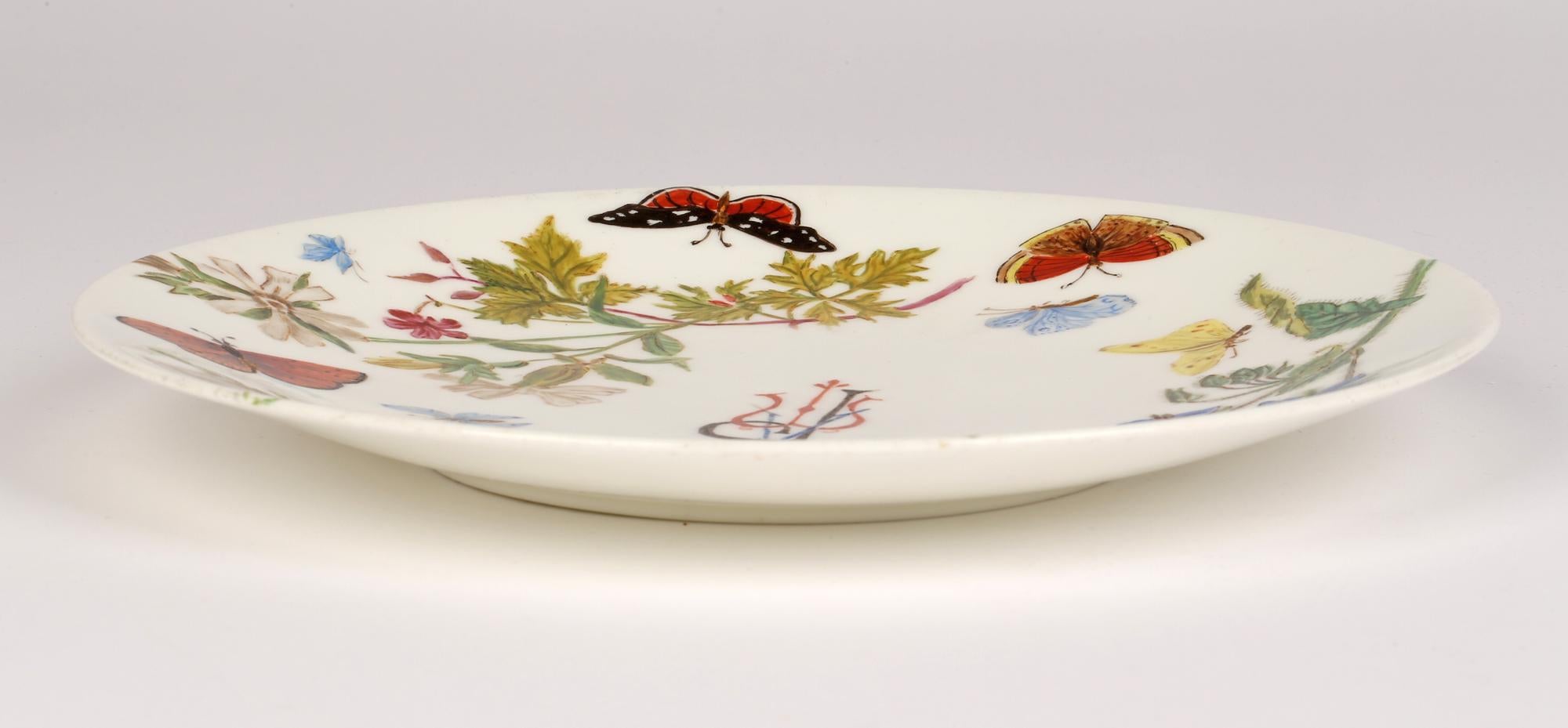 An unusual and stylish Aesthetic Movement Minton porcelain cabinet plate hand painted with flowers and butterflies with initials APM and dating from 1890. This finely made plate is of simple round form with a slightly raised edge and is very finely