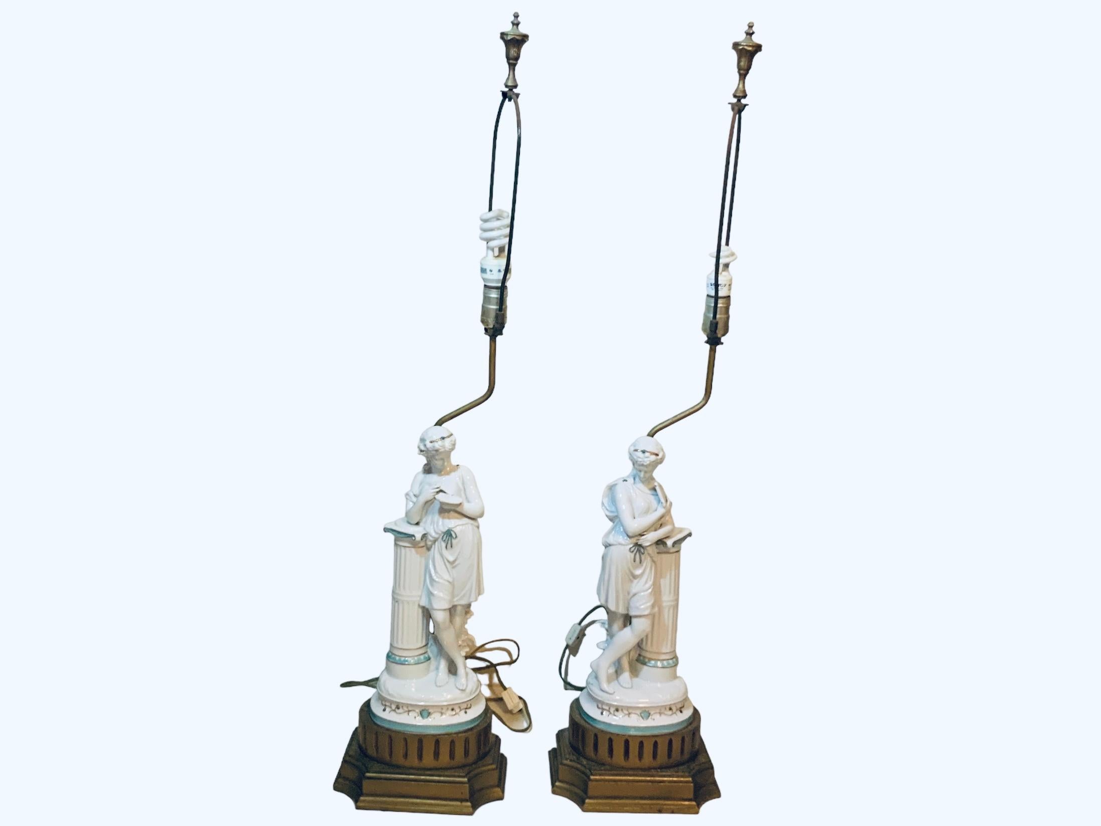 This is a Minton Porcelain sculptures lamps. They are hand painted glazed white porcelain with some light turquoise ornaments. It depicts two barefoot Greek/ Roman young ladies figures that are standing in front of large columns pedestals. One who