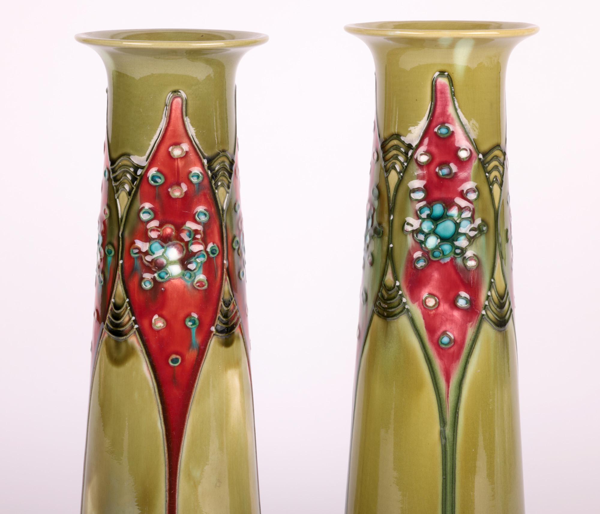 A very stylish and scarce pair Minton Secessionist Art Nouveau tube lined art pottery vases dating from around 1900. The pottery vases stand on a wide round stepped foot and are of tall tapering cylindrical shape with a round trumpet shape rim. The