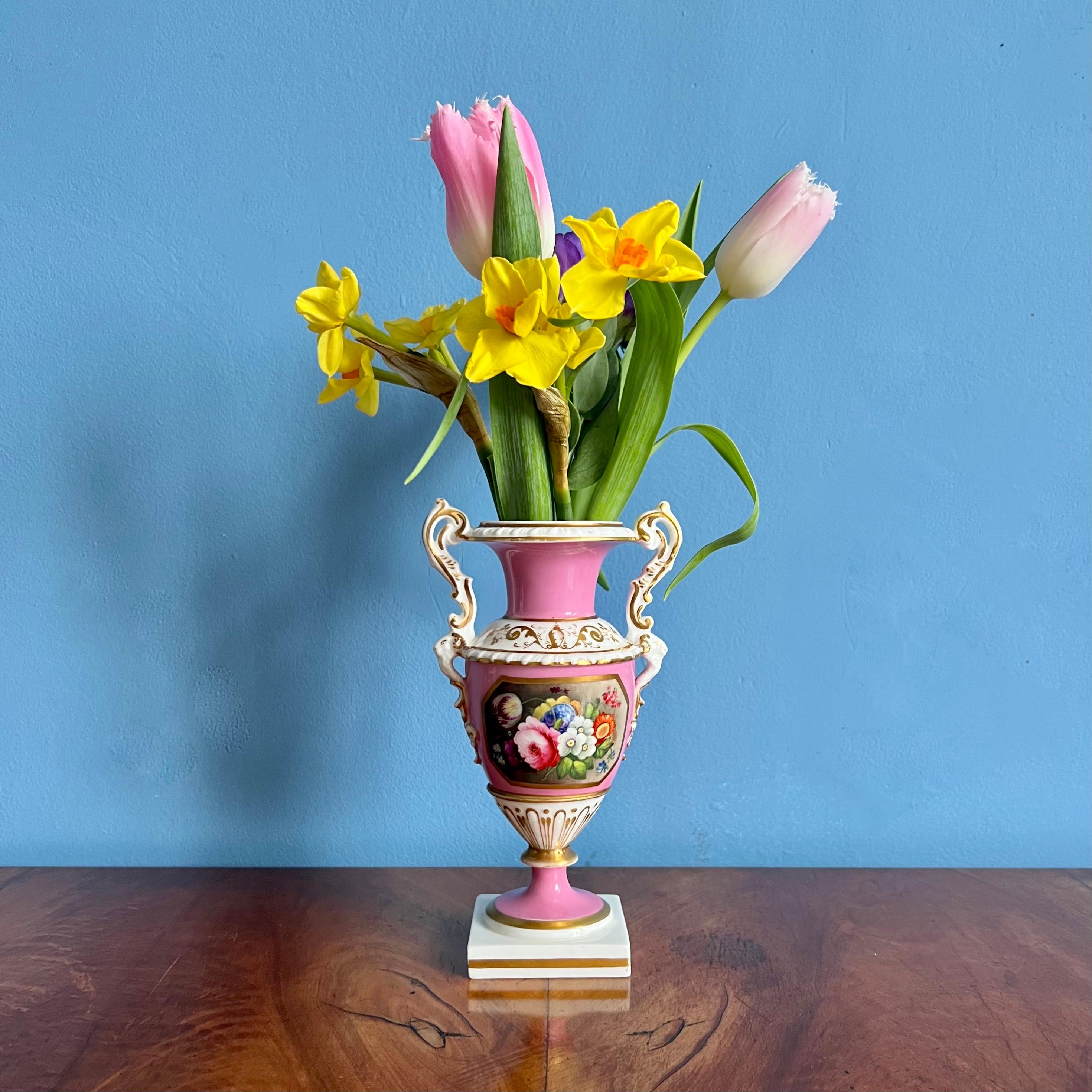 This is a stunning vase made by Minton between 1830 and 1835. The vase has a bright pink ground with a beautiful floral reserve in the front, and charmingly shaped white handles with rams heads.

Minton was one of the pioneers of English china