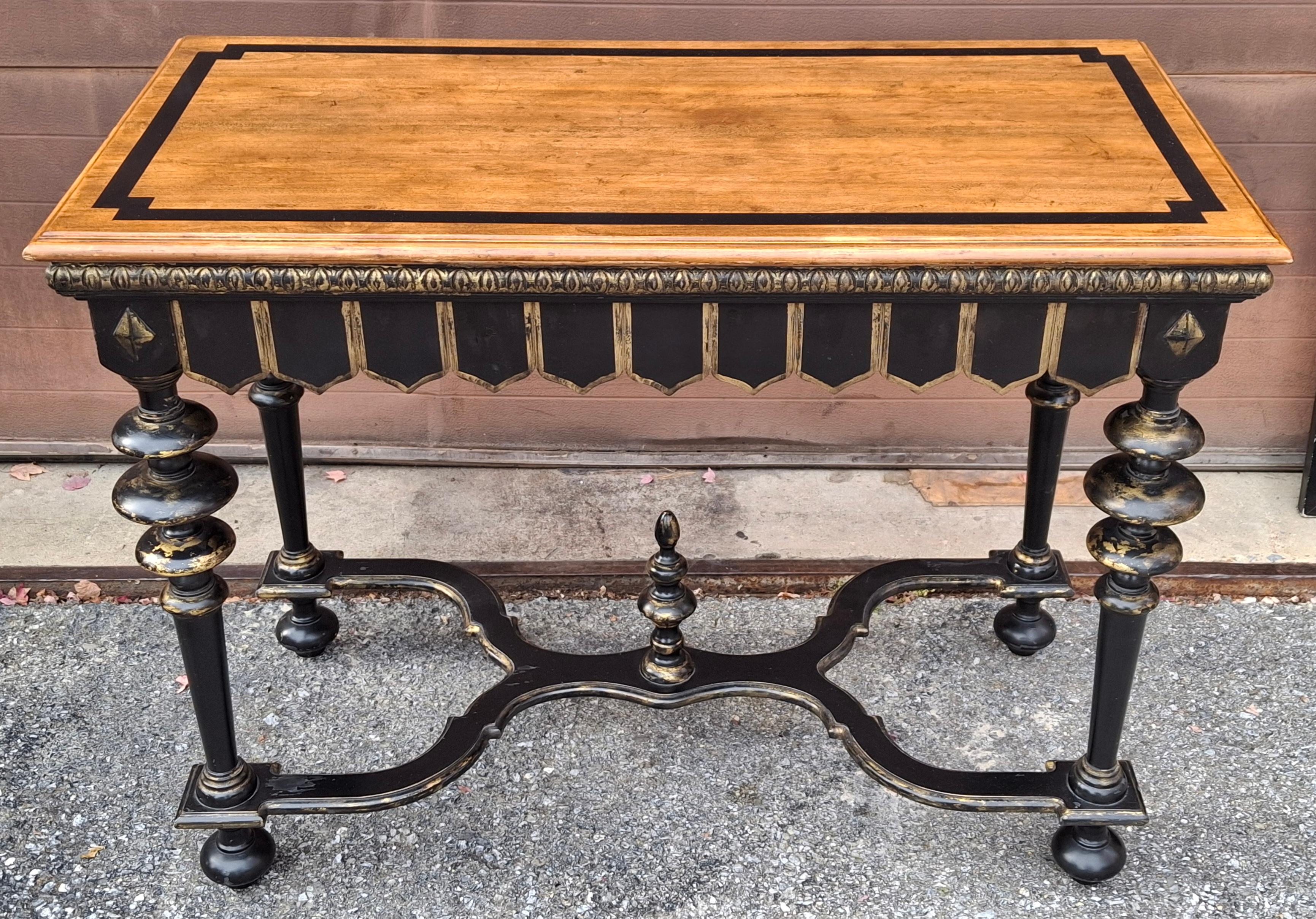 The Villanova Console Table from the Las Palmas Collection by Minton-Spidell is a Spanish Baroque-style console table featuring a partial gilt, ebonized, and cherry finish. 
The table has a rectangular wooden top and a trestle-style base. 
The