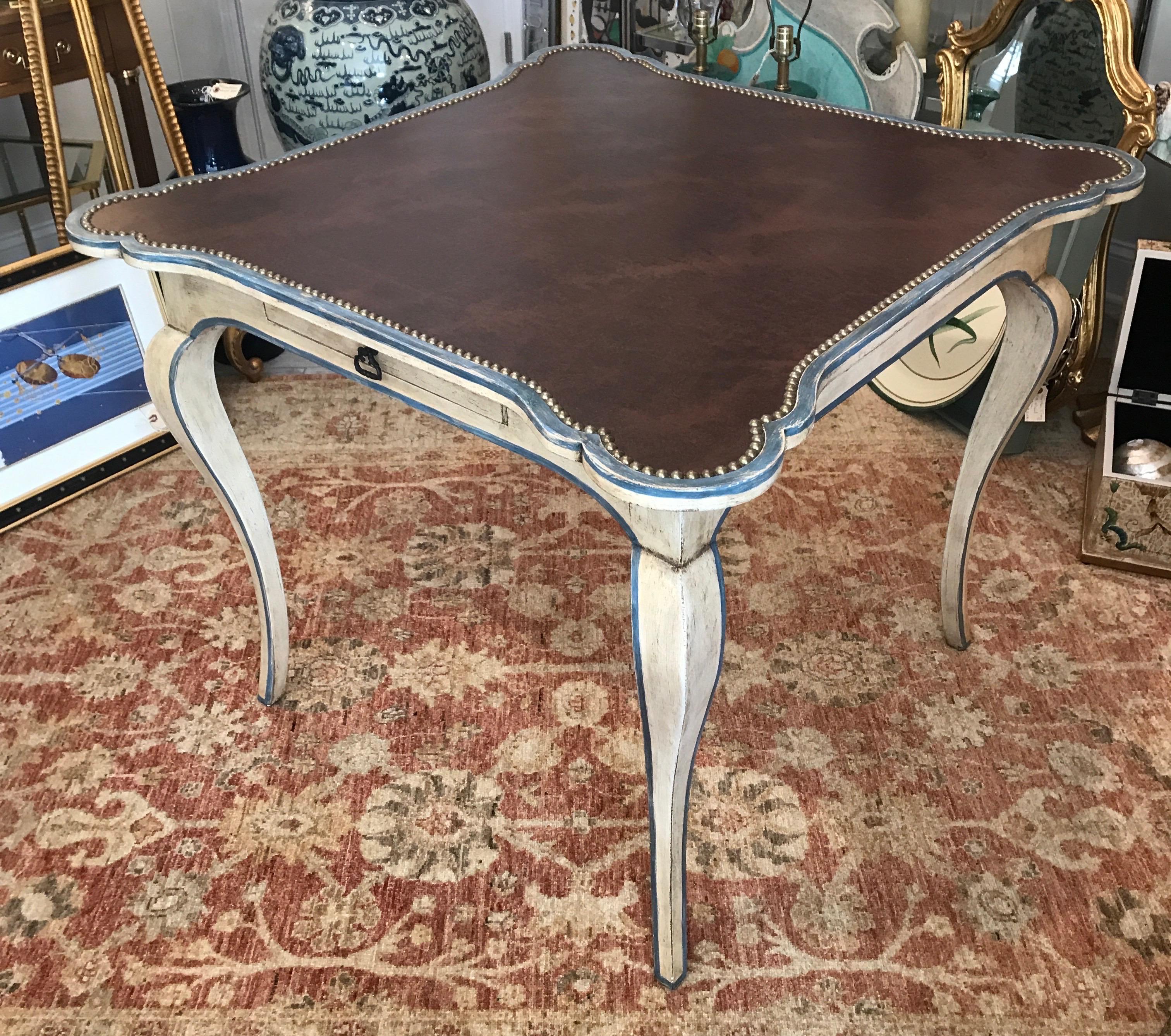 Minton Spidell cabriolet leg country French game table with leather top and studs. Antique white and blue painted finish.