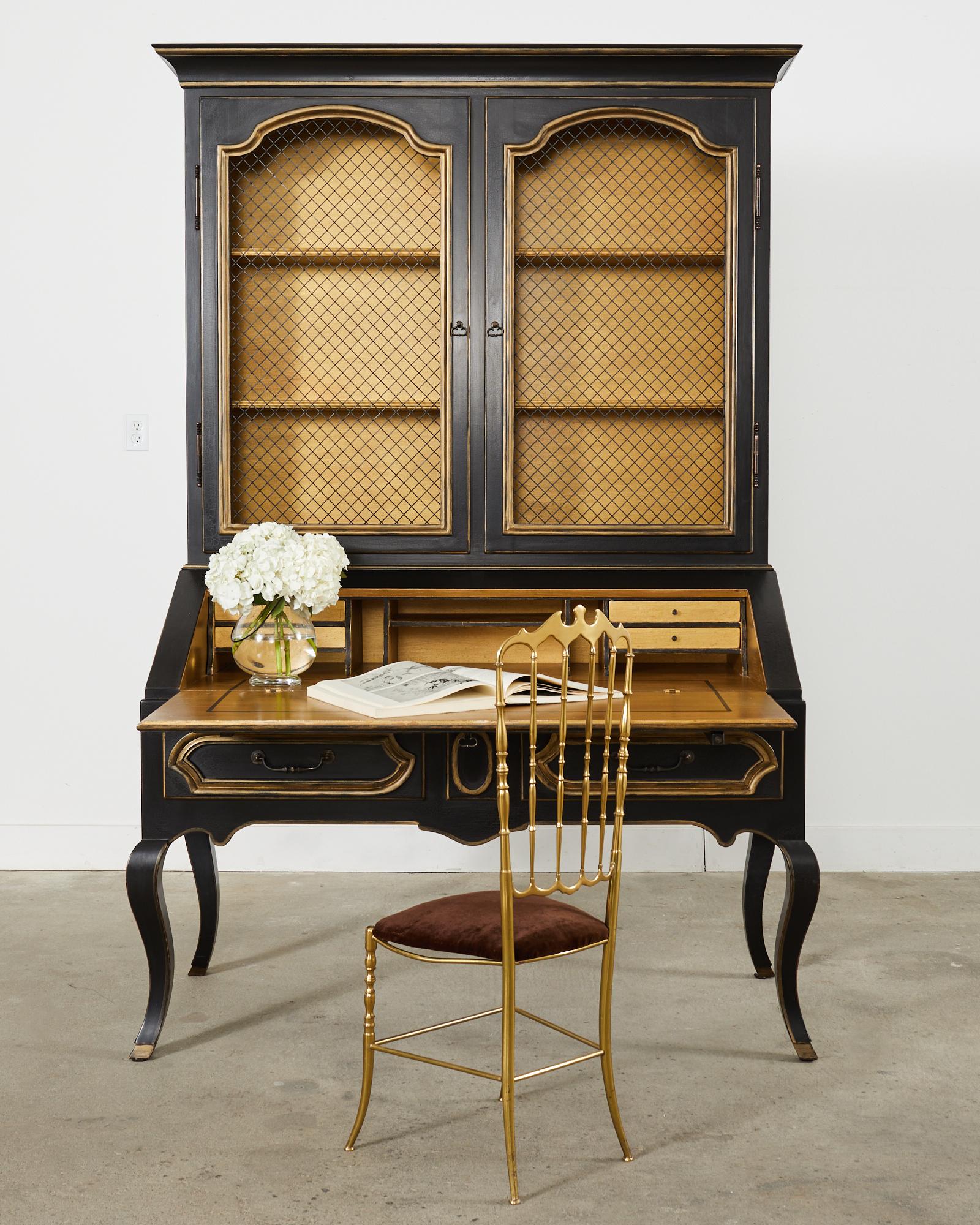 Dramatic secretaire bookcase or bibliotheque hand-crafted by Minton-Spindell Los Angeles, CA. The two-part case features an ebonized lacquer finish with parcel gilt accents. The lacquer has a desirable aged patina with craquelure. The secretaire is