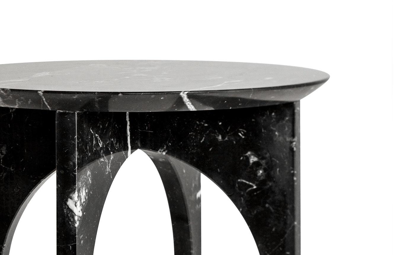 The Minus Side Table is a minimalist style side table made of treated Marquina marble. This side table is composed of a circular marble top, supported by four marble legs forming two pointed arches. All of the elements are assembled in a logical and