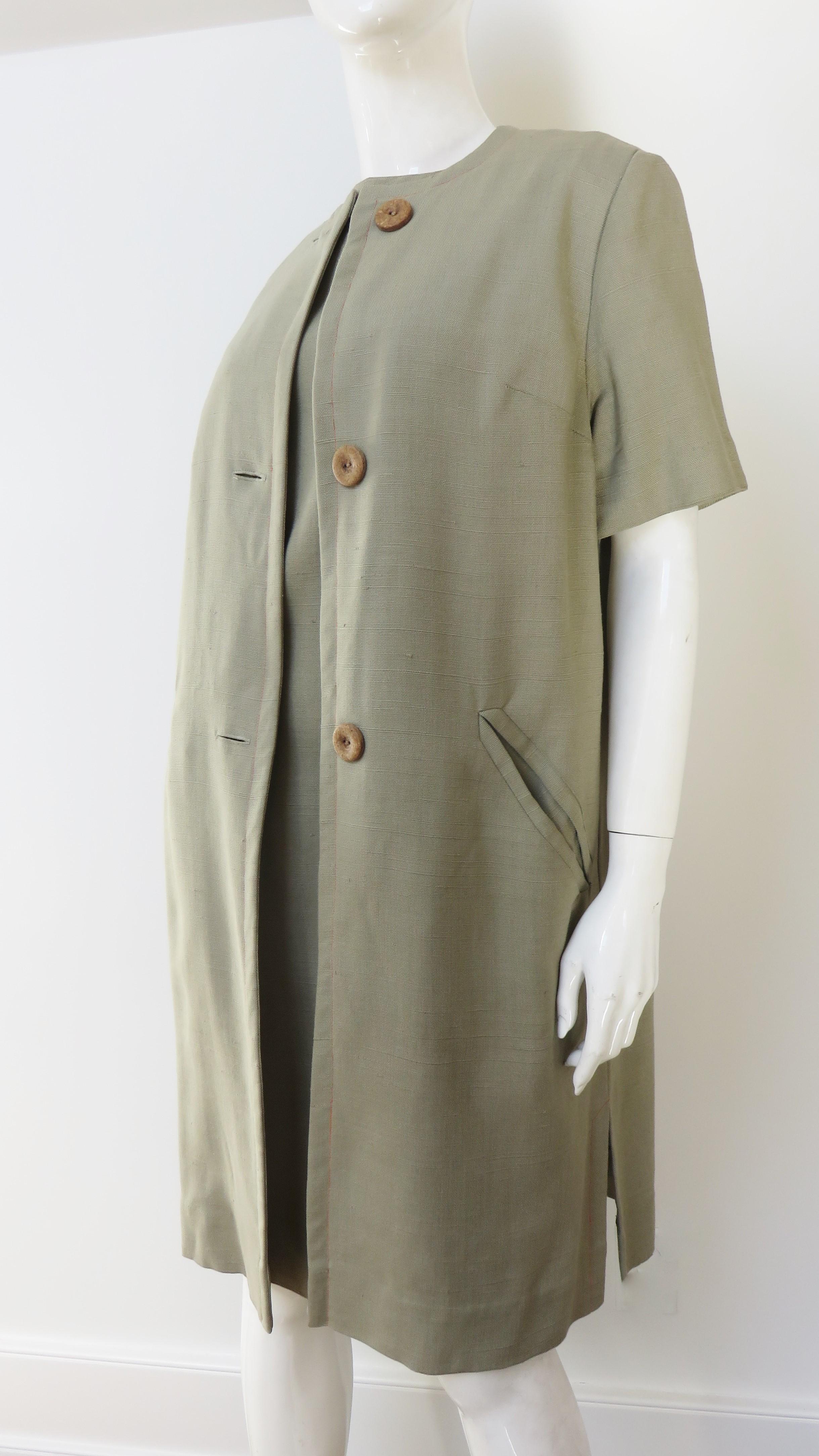 A fabulous khaki linen dress and coat set by Minx Modes. The shift dress is sleeveless with a front yoke, back kick pleat and contrasting orange topstitching.  The matching jacket has short sleeves, front welt pockets, front buttons and slits at the