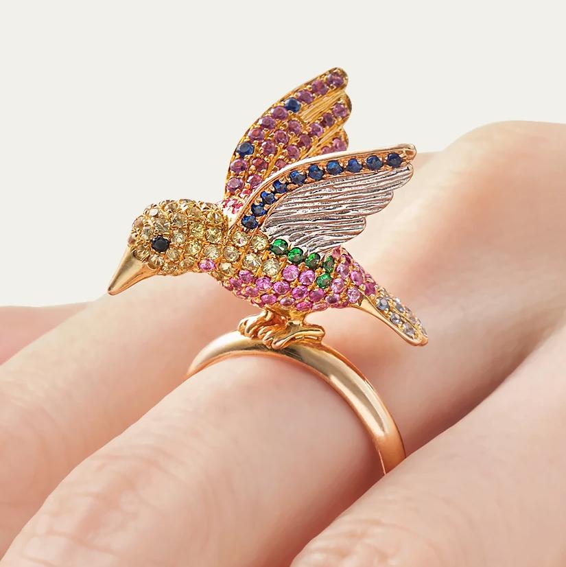 Japanese jeweler creates a life-like bird but colors it like a jewel. This ring excites the imagination with pink, yellow and blue sapphires, diamonds and green garnets. Don’t let her fly away.

Contemporary design
Diamond weight is 0.20 carats
Blue
