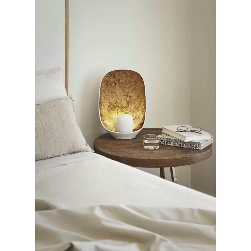 A porcelain table lamp which stands out for its original design, featuring a beautiful etching in golden luster.

This piece is made in white matte porcelain, with a background decorated in golden luster which, when lit, produces a delicate effect