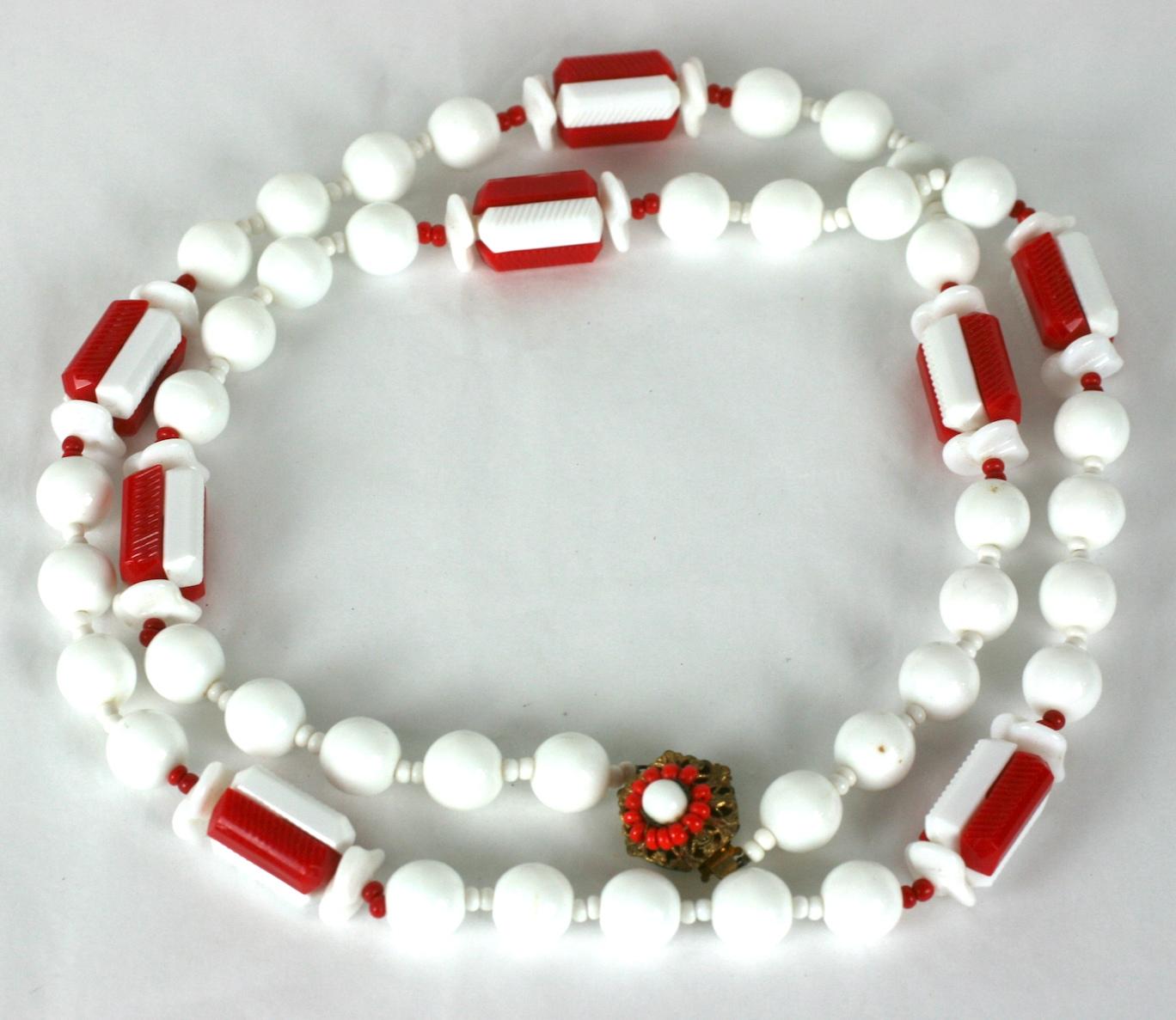 Miriam Haskell chalk white and cherry red necklace. Of alternating round white beads and eight composed stations of red and white pieced spacers.
Signature clasp of gilt filigree metal, hand sewn with white and red beads. 
Excellent