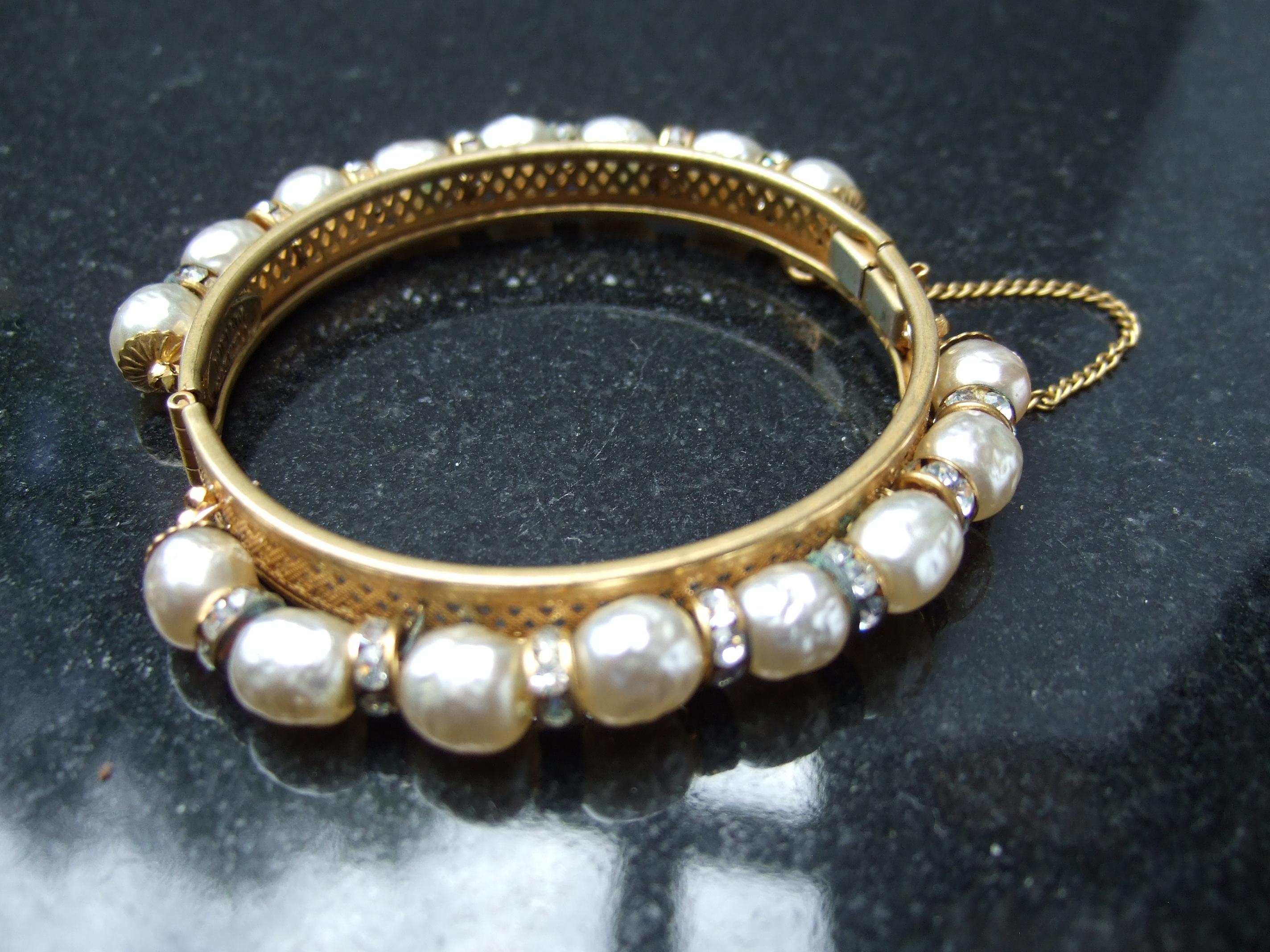 Miriam Haskell Elegant glass enamel pearl hinged bracelet c 1950s
The mid century brass filigree hinged bracelet is embellished 
with a band of glass enamel baroque style pearls juxtaposed 
with subtle clusters of clear diamante crystals 

The