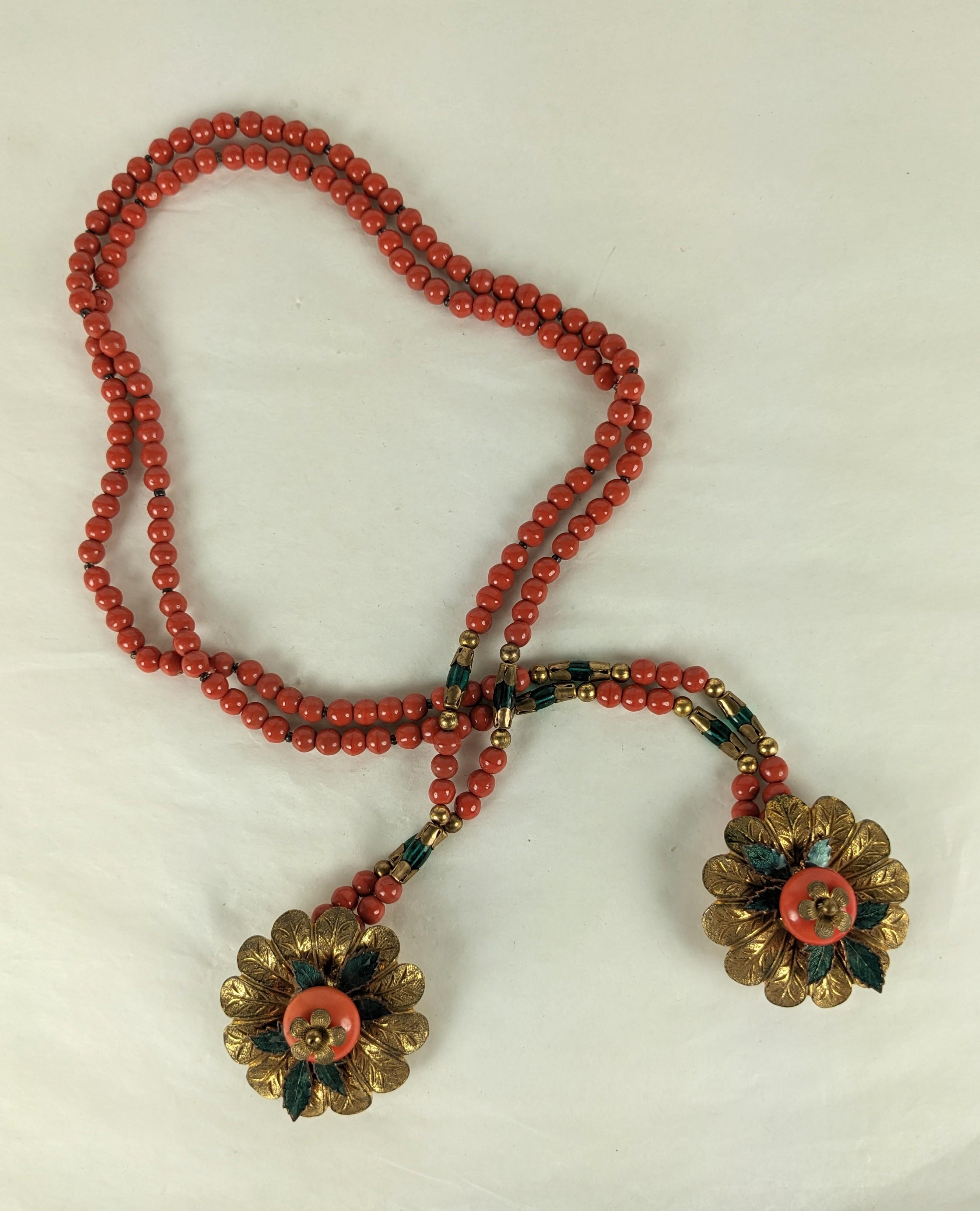 Miriam Haskell Early Wrap Clip Lariat of faux coral and emerald pate de verre beads with gilt floral stations on each end. Each clip station is decorated with a large cabochon and enamel leaves from the late 1930's. 
These lovely lariats have clip