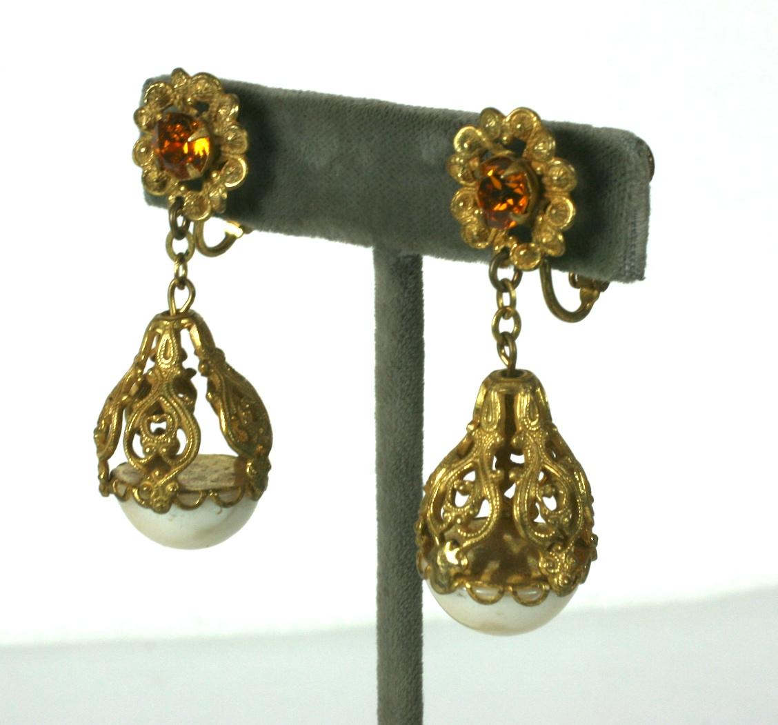 Miriam Haskell Long Filigree Pearl Drop Earrings with citrine paste flowers at ear. Large faux pearls are held by a filigree cage to form the ear pendants. Signature Russian Gilt finish. 
Adjustable Haskell clip back fittings. 