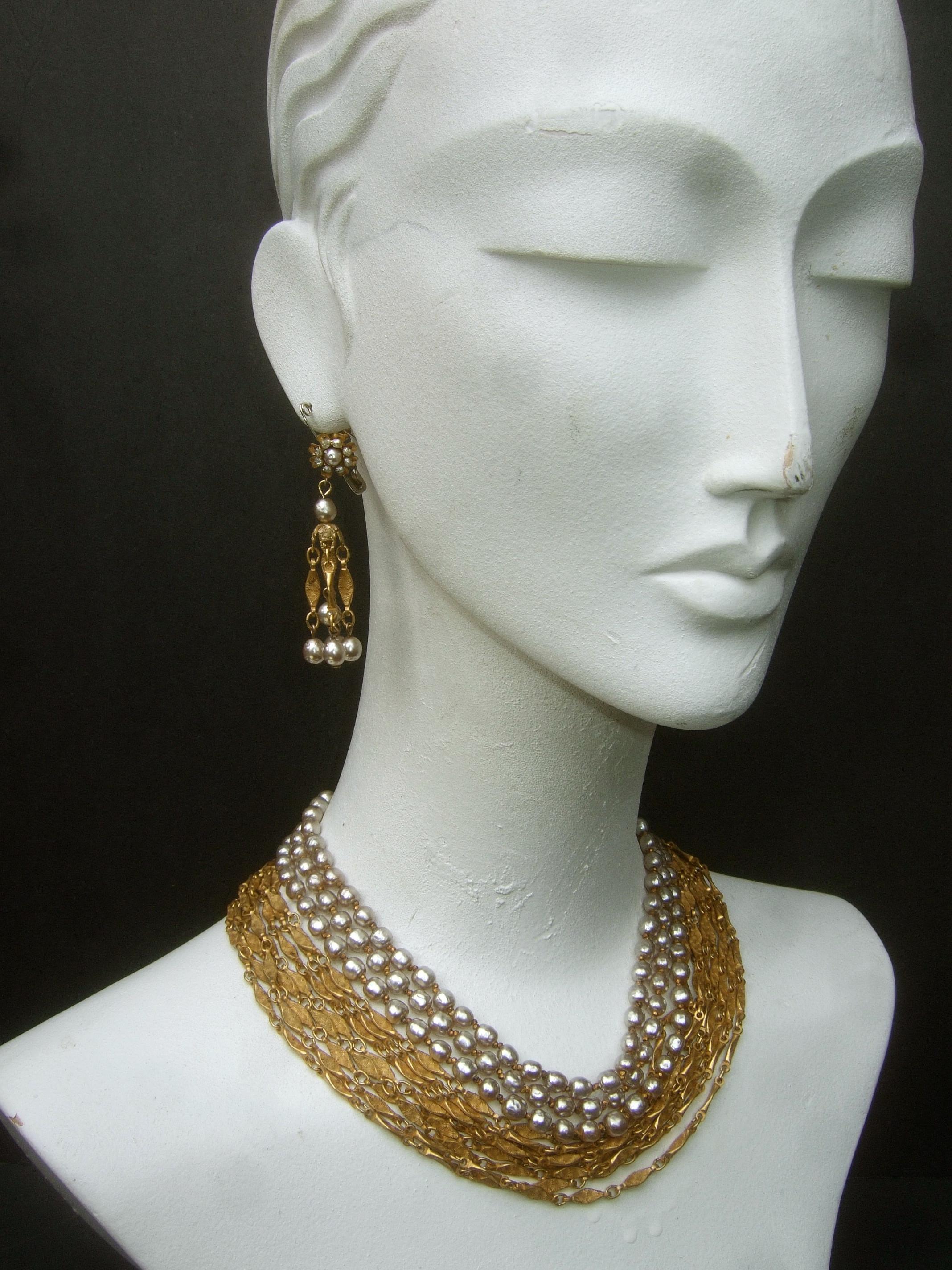 Miriam Haskell Exquisite glass baroque pearls & chains choker necklace & earrings set c 1960s
The elegant graduated choker necklace is comprised of three rows of glass enamel baroque style pearls
Embellished with eight rows of graduated gilt metal