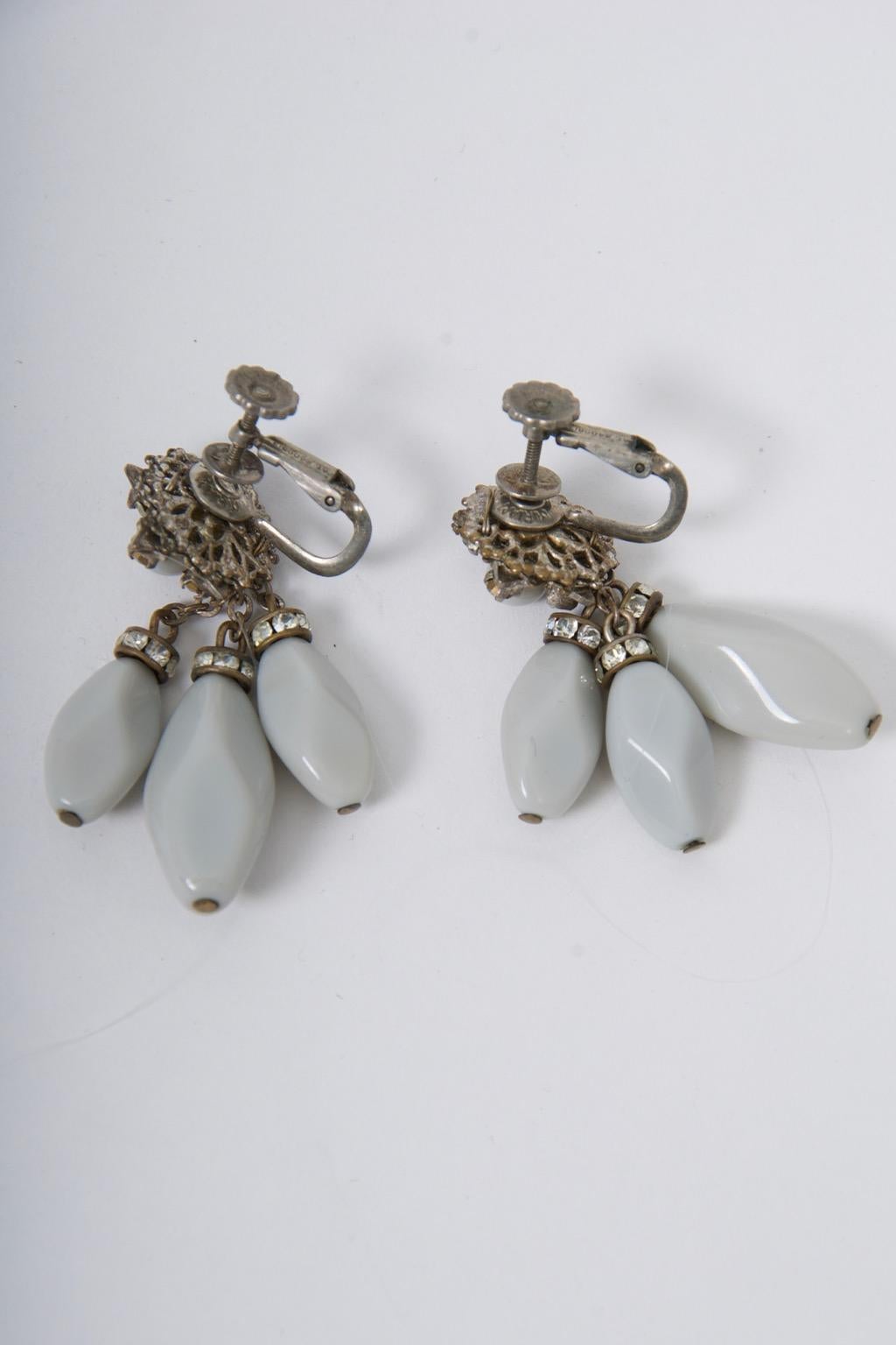 Unusual and sophisticated coloring in these c. 1960 Miriam Haskell earrings, featuring three smoothly faceted gray bead drops below rhinestone rondels, and suspended from a typical pierced Haskell earpiece centering a round gray bead. Clip-on
