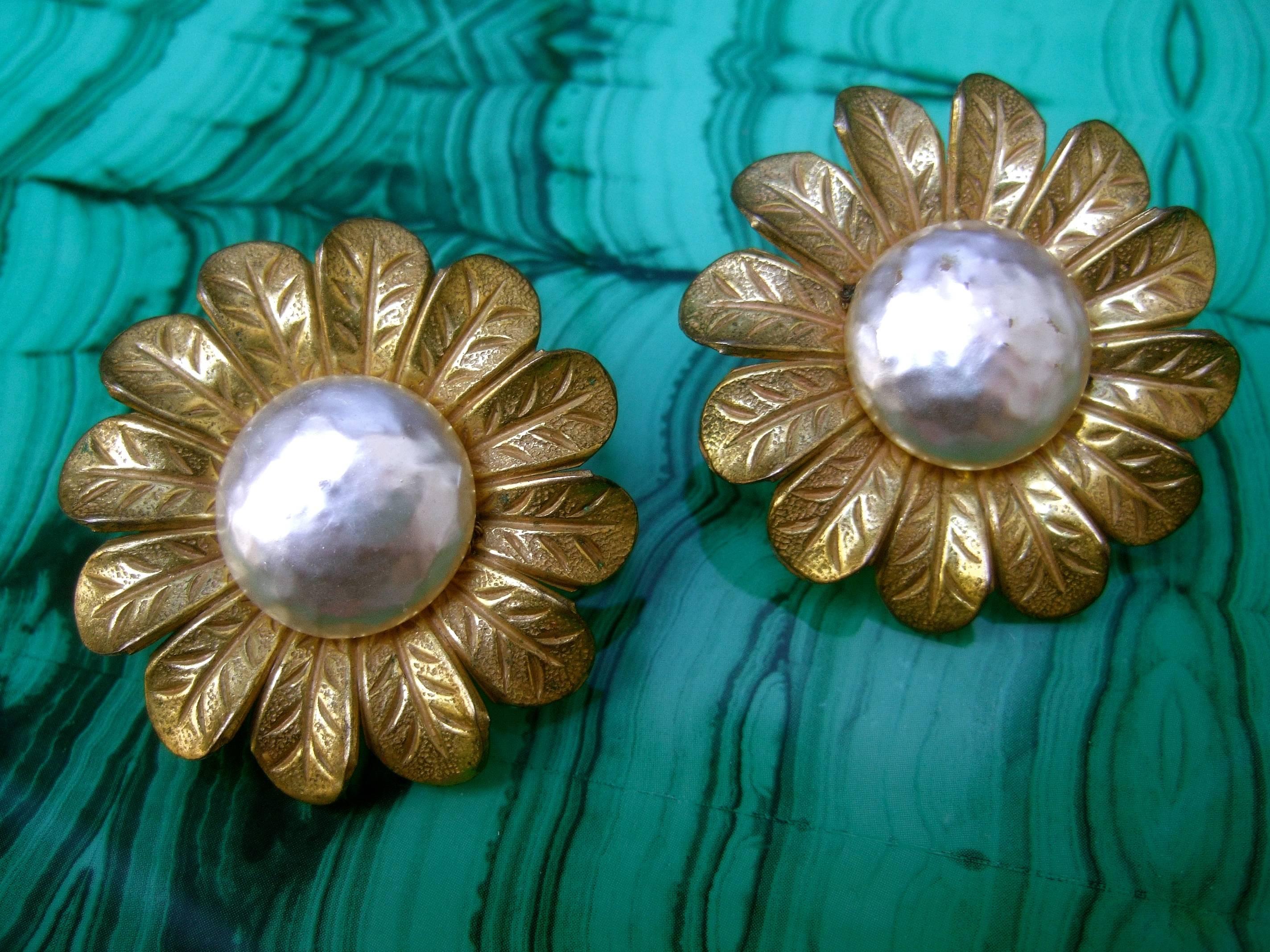 Miriam Haskell Massive baroque glass pearl sun flower earrings c 1960
The elegant clip on earrings are adorned with a large glass
enamel baroque style pearl in the center

Circling the glass enamel pearl is a wreath of Russian gilt metal
etched