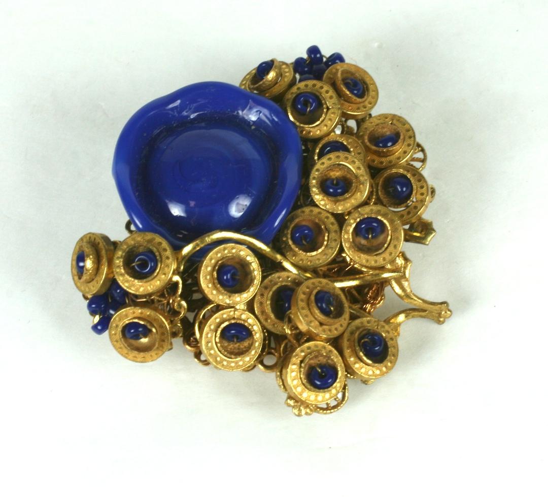 Miriam Haskell Modernist flower head brooch composed of a hand made lapis pate de verre abstract flower head bead with leaves in Russian Gilt finish. The leaves are  structured from textured rings and hand sewn lapis seed beads.
Excellent Condition,