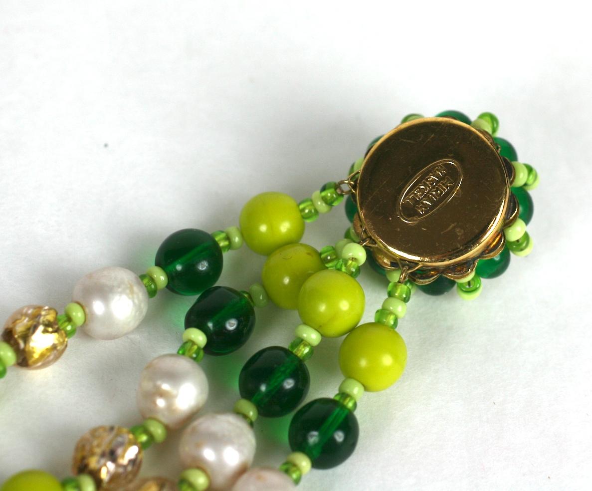 Bracelet inhabituel de Miriam Haskell composé de perles en pate de verre de différentes teintes d'émeraude et de vert pois, et de perles en verre vénitien de couleur or  et de fausses perles baroques d'eau douce. Fermoir rond à tête de fleur en