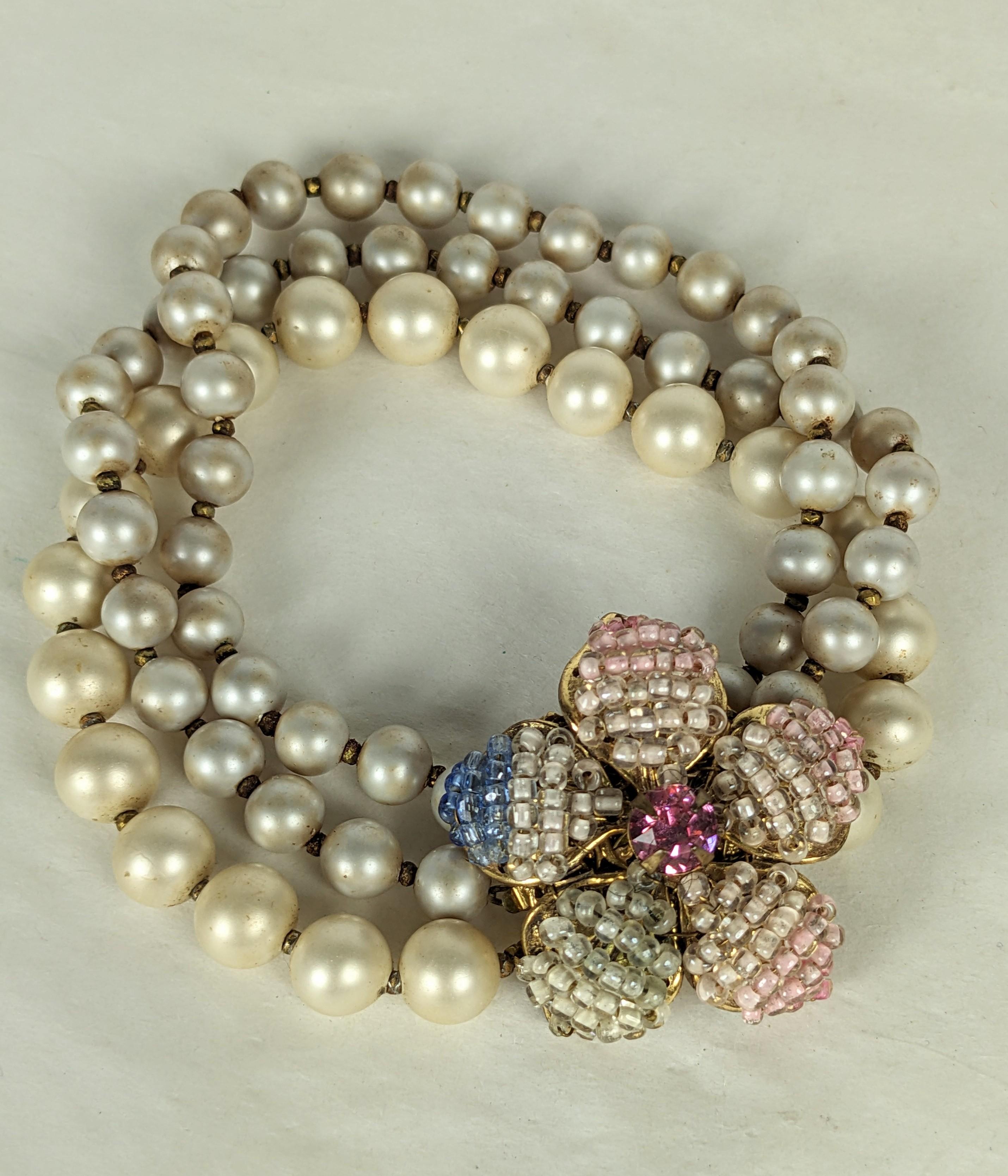 Miriam Haskell three strand  two toned faux pearl bracelet ,with minute  gilt  
 faceted cut steel spacers. The hand sewn  pastel ombre beaded flower head clasp  in shades of blue and pink with pink crystal rhinestone  center.
1950's USA. Signed