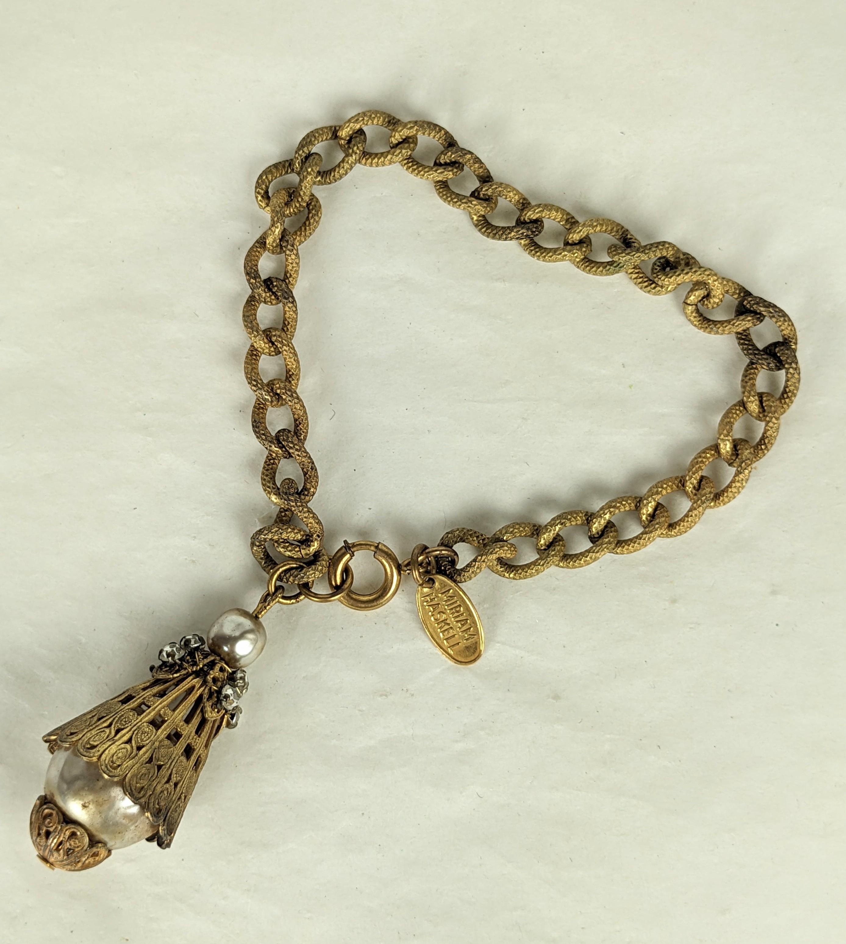 Bracelet-bouton en fausses perles baroques de Miriam Haskell. Composée d'une chaîne à maillons texturés en plaques dorées russes, d'une perle baroque moyenne et grande et de filigranes dorés de style néo-étrusque. Le bouton en forme de lanterne