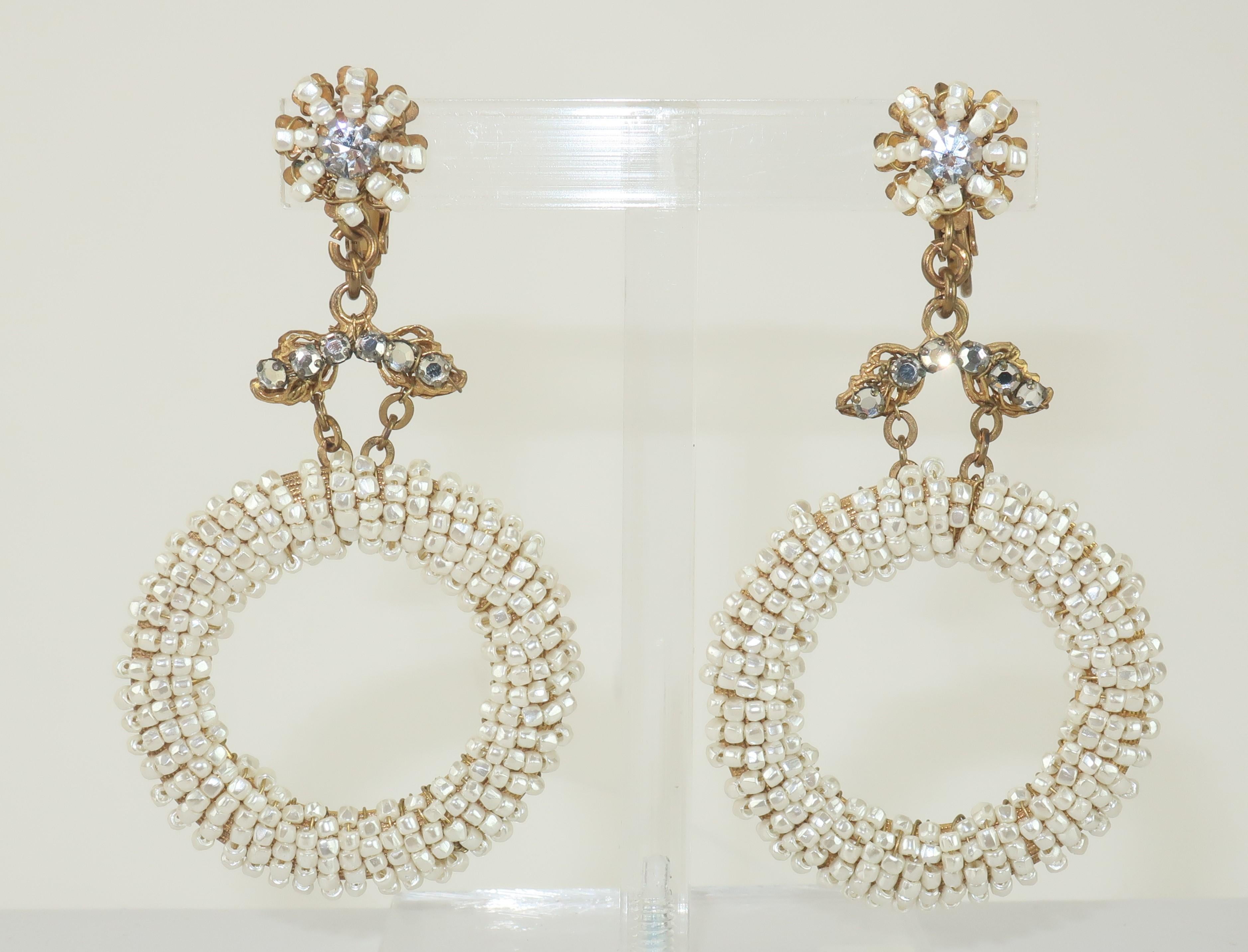C.1960 Miriam Haskell hoop earrings with j-ring clip on hardware.  These ethereal earrings are a lovely combination of Haskell's traditional baroque aesthetic in a more youthful silhouette.  The tiny seed pearls are wired to a gilt gold base and