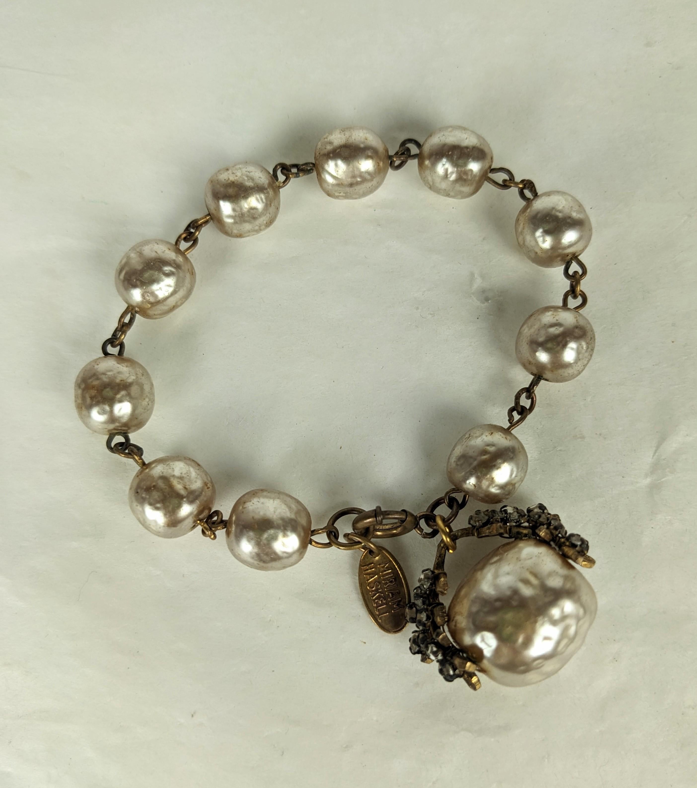 Miriam Haskell faux baroque pearl and gilt fob bracelet. Composed of signature  faux baroque pearl links with a  Russian gilt delicate  double branch filigree and baroque pearl charm.  Decorated with hand sewn crystal rosemontes.

 Excellent
