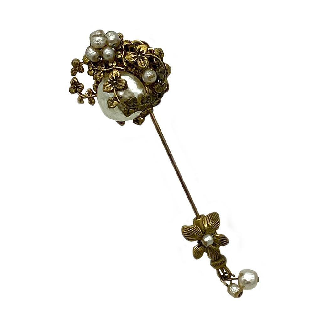 This is a Miriam Haskell pearl stick pin/brooch. This is a gilt Russian gold metal flowers stick pin that is hand wired with Niki pearls and on the end of the pin has a flower and the dangling pearls.  It comes from a Florida estate and has been