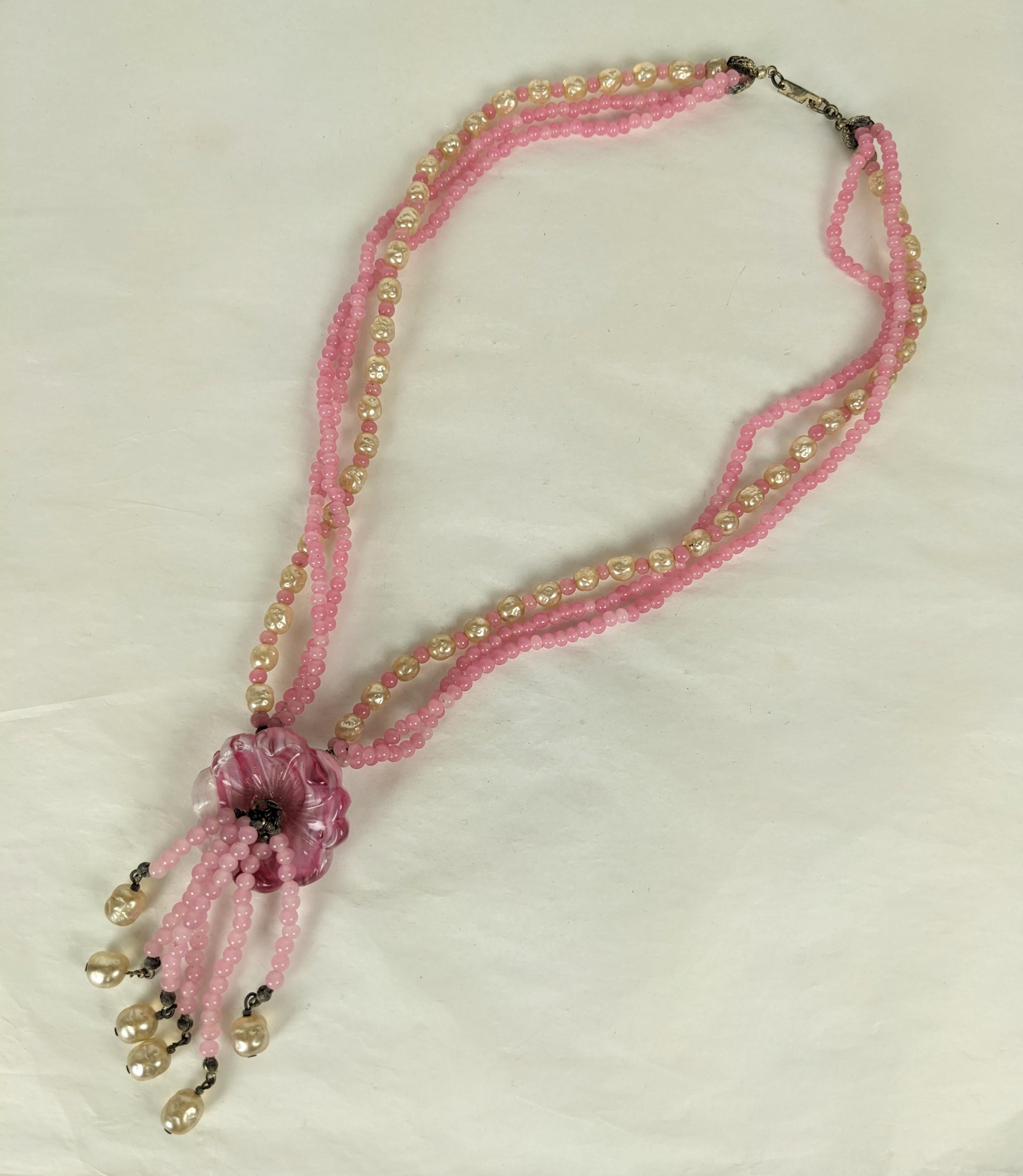 Lovely Miriam Haskell 3 strand torsade necklace of rose pink Gripoix pate de verre glass beads mixed with signature baroque pearls and silver gilt plate filigrees. Molded glass flower with 5 strand pendant center tassel. Signed Miriam Haskell on