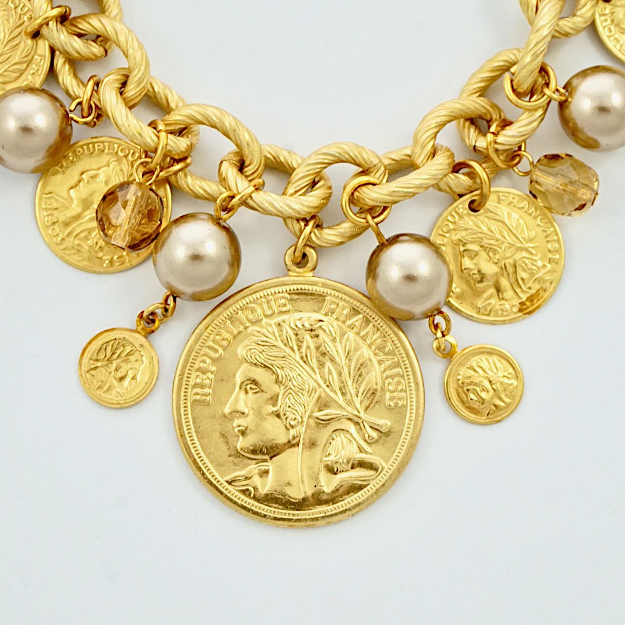 Fabulous Miriam Haskell Russian gold plated charm bracelet, with pale gold faux pearls and faceted citrine glass, and Greek and French decorative coins. Measuring length 20.3 cm / 8 inches, and the largest coin is diameter 2.9 cm / 1.14 inch. The