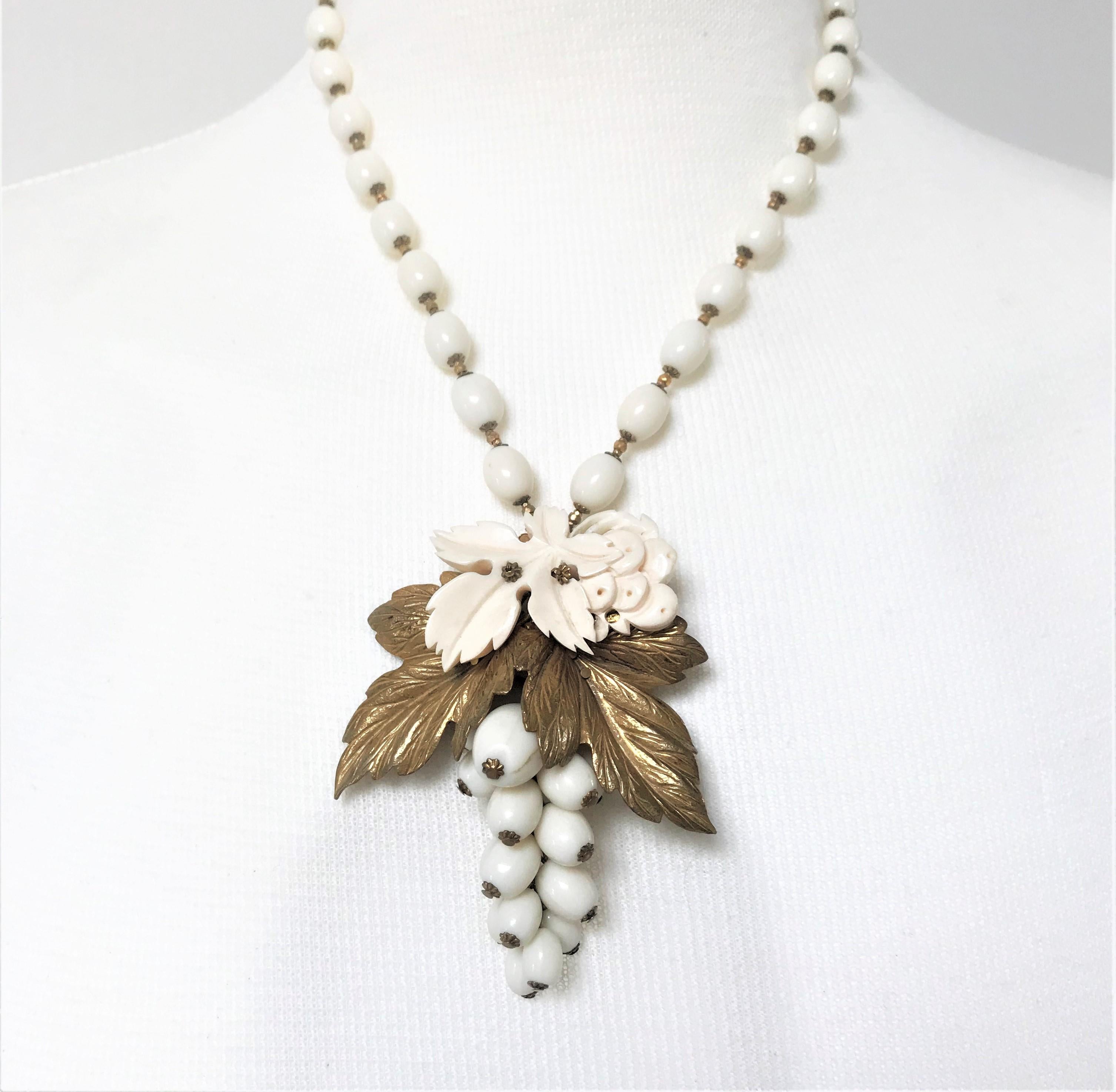 A very nice set by Miriam Haskell necklace and ear clips from the 50s USA. It consists of a chain with ivory colored 1 cm glass beads. A grape hanging from the same pearls as the necklace, 2 gilded vine leaves and smaller leaves carved over them. In