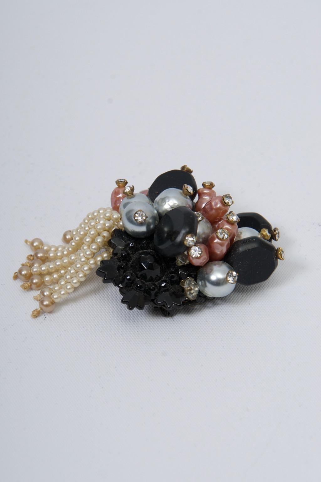 Broche vintage unique de Miriam Haskell, vers les années 1960, incorporant un ensemble de perles contrastées, en noir, gris pâle et saumon, chacune surmontée d'un petit cristal, l'élément principal suspendant un pompon de minuscules perles blanches.