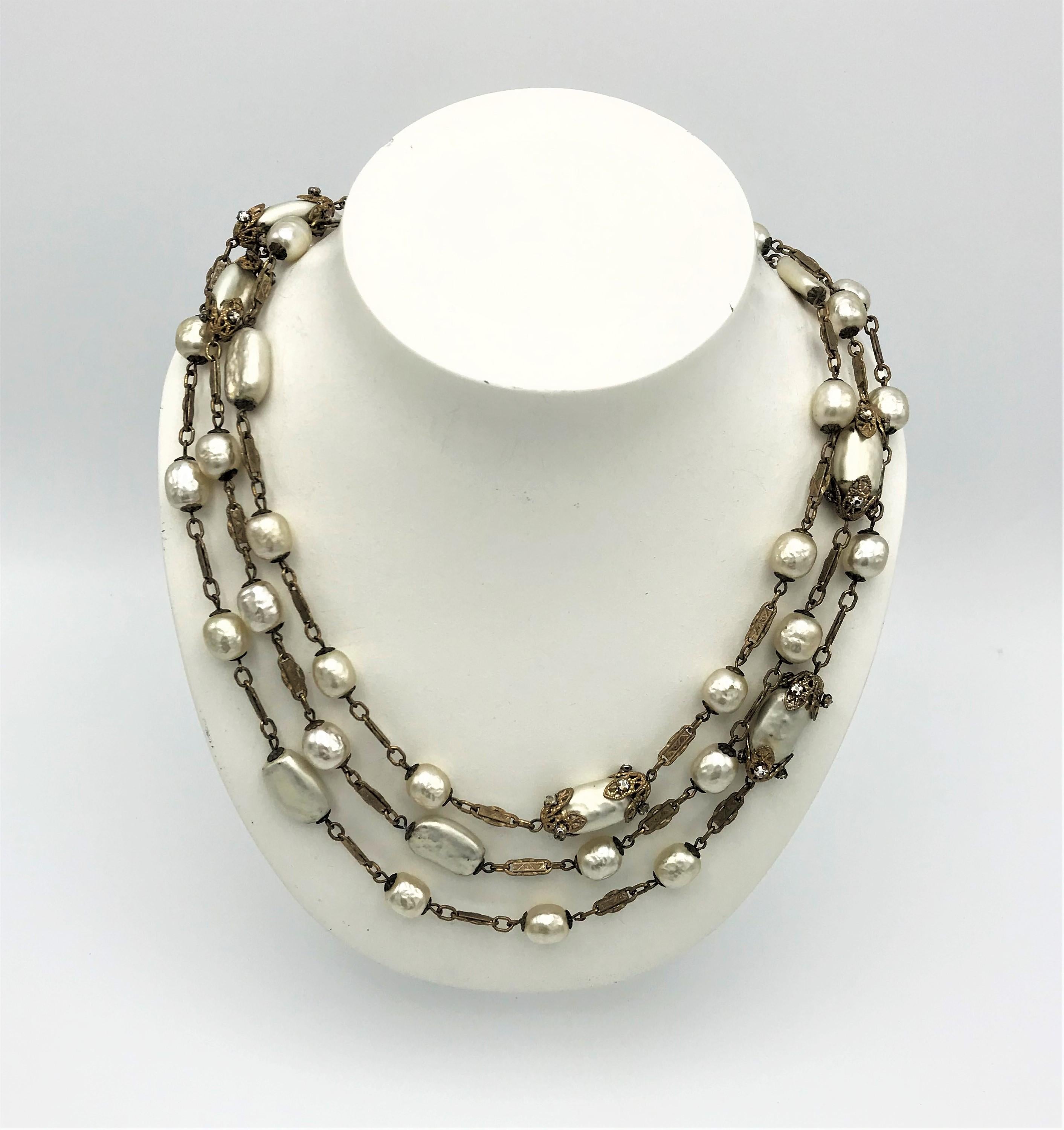 Exquis et long collier Miriam Haskell des années 1950 avec différentes perles baroques.  Ronde, ovale plate et ovale bordée de fines feuilles et d'accents en strass. Le collier est muni d'un fermoir à anneau à ressort et porte à côté la plaque de