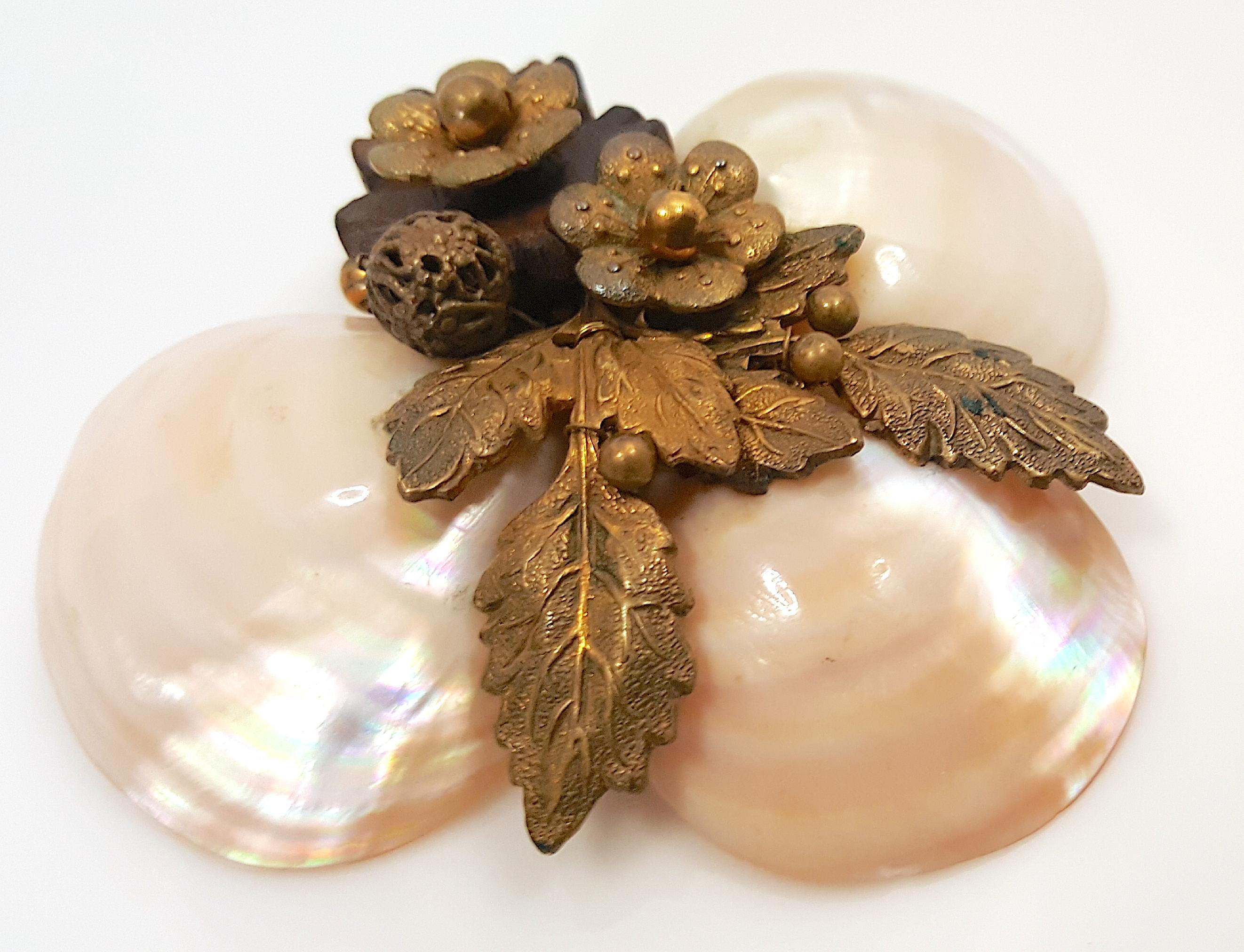 This early Miriam Haskell lacquered-shell and brass-decorated clip brooch was created by Frank Hess, her first designer since 1926. The 1930s brooch features three seashells supporting an asymmetrical arrangement of textural Russian-gold gilt