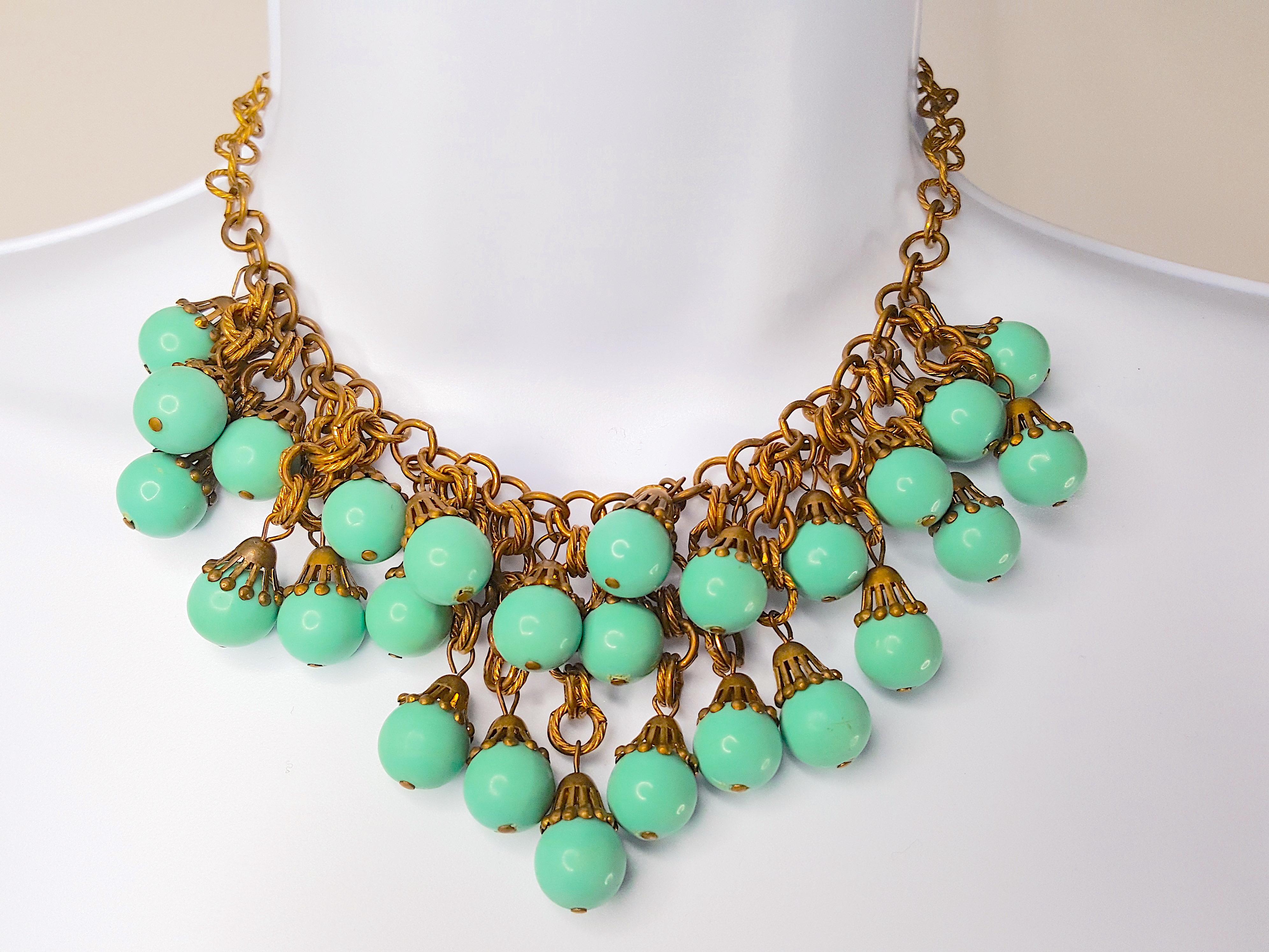 Around 1930, Miriam Haskell's first designer Frank Hess designed this Russian-gilt brass ribbed-chain link bib necklace featuring 27 strands of varying length each wired to aqua faux-turquoise pressed glass beads with characteristic gold