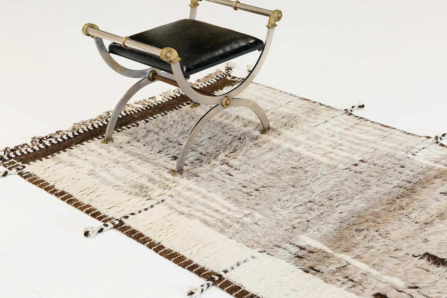 A dark brown handwoven base flat-weave with embossed detailing streams through this white wool shag rug with heather grey line work moving irregularly from top to bottom. Inspired by the Atlas Mountains in Morocco for the modern design world.