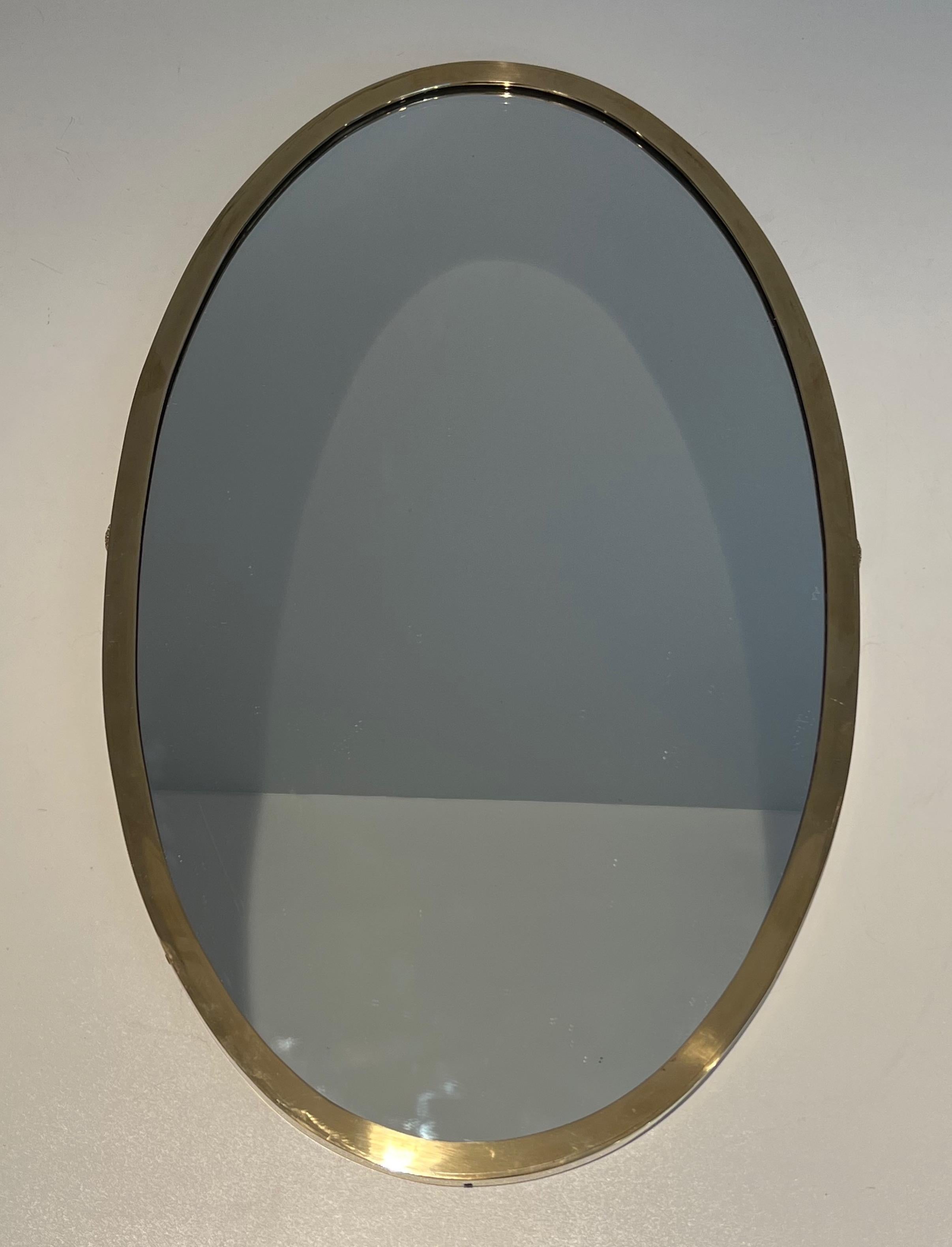 This neoclassical style oval mirror is made of brass and mirror. This is a very simple and pure piece with decorations on each side. This is a French work in the style of famous Maison Jansen. Circa 1940