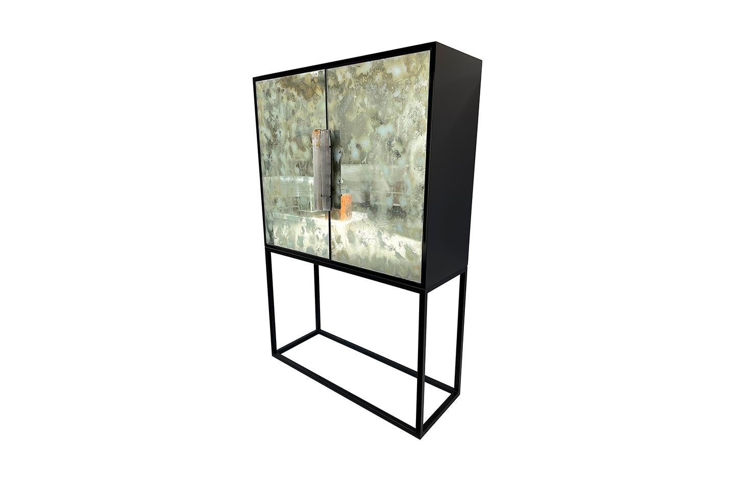 This Bar  Cabinet By Ercole Home stands on a sleek Black Metal Base.
The wood case is in black lacquer, glossy finish. 
The interior is in black lacquer, glossy finish.
The two doors are covered by Eglomizee  Hand Painted Mirror in a White Dust,