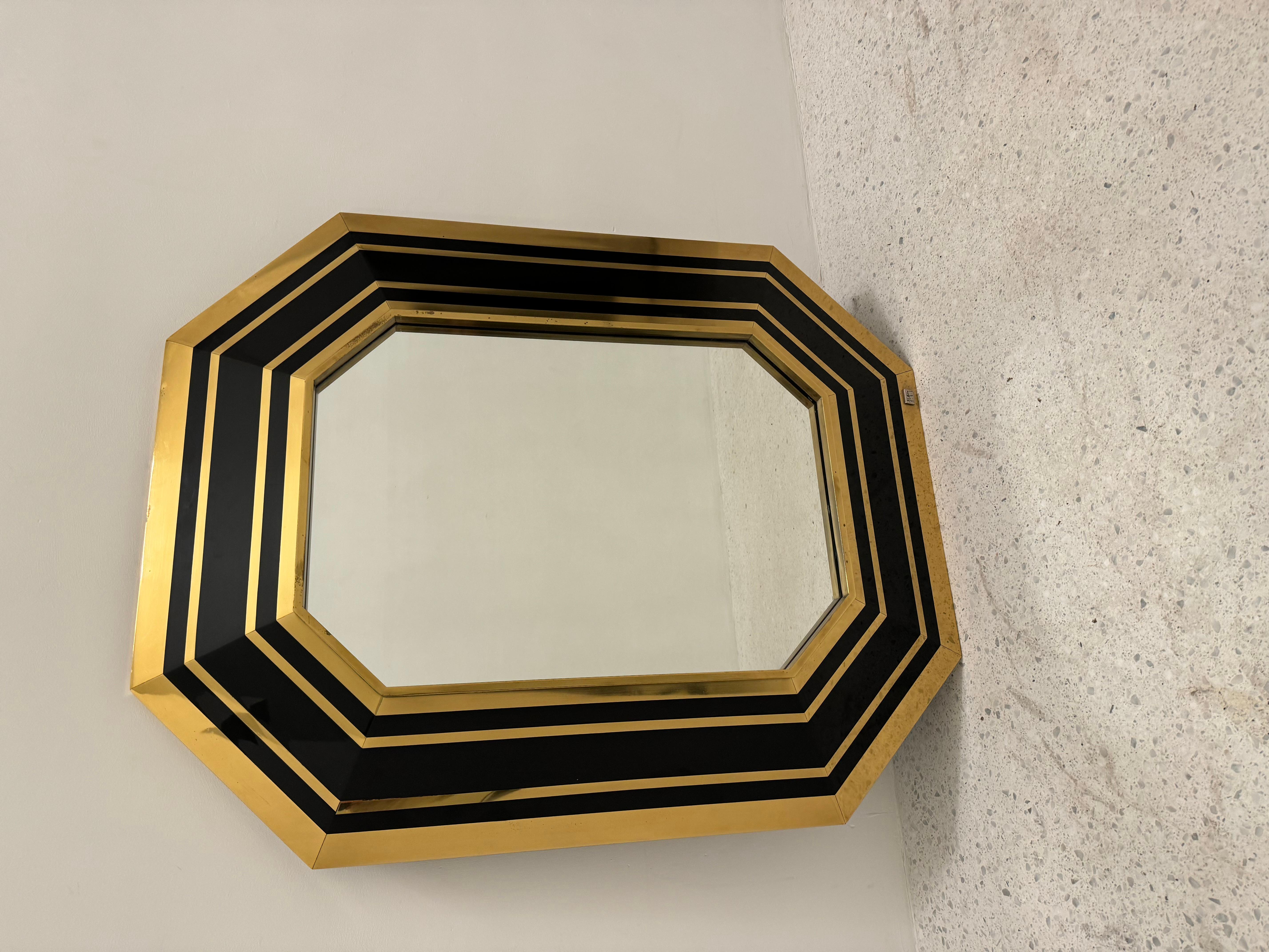 Miroir octogonal conçu et signé par le designer français Jean Claude Mahey. Le cadre du miroir alterne des bandes noires et des bandes dorées pour un aspect majestueux.