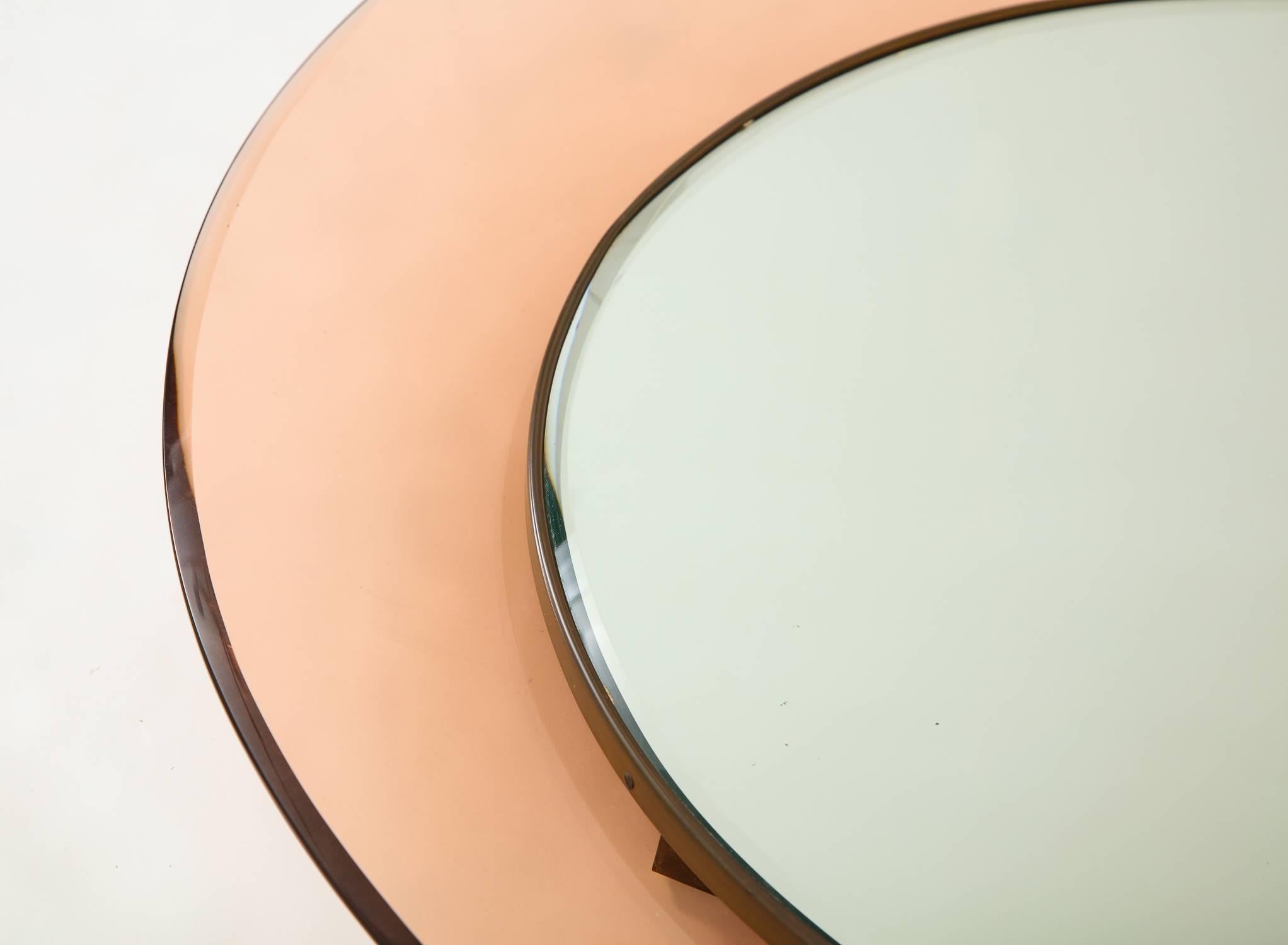 Round mirror by Max Ingrand for Fontana Arte, Italy 1966. Bevelled mirror set in a brass frame surrounded by a concave glass frame in pale rose. All original, original mirror date stamped 20 Mar 1968 on the reverse. Model number 1669, documented in
