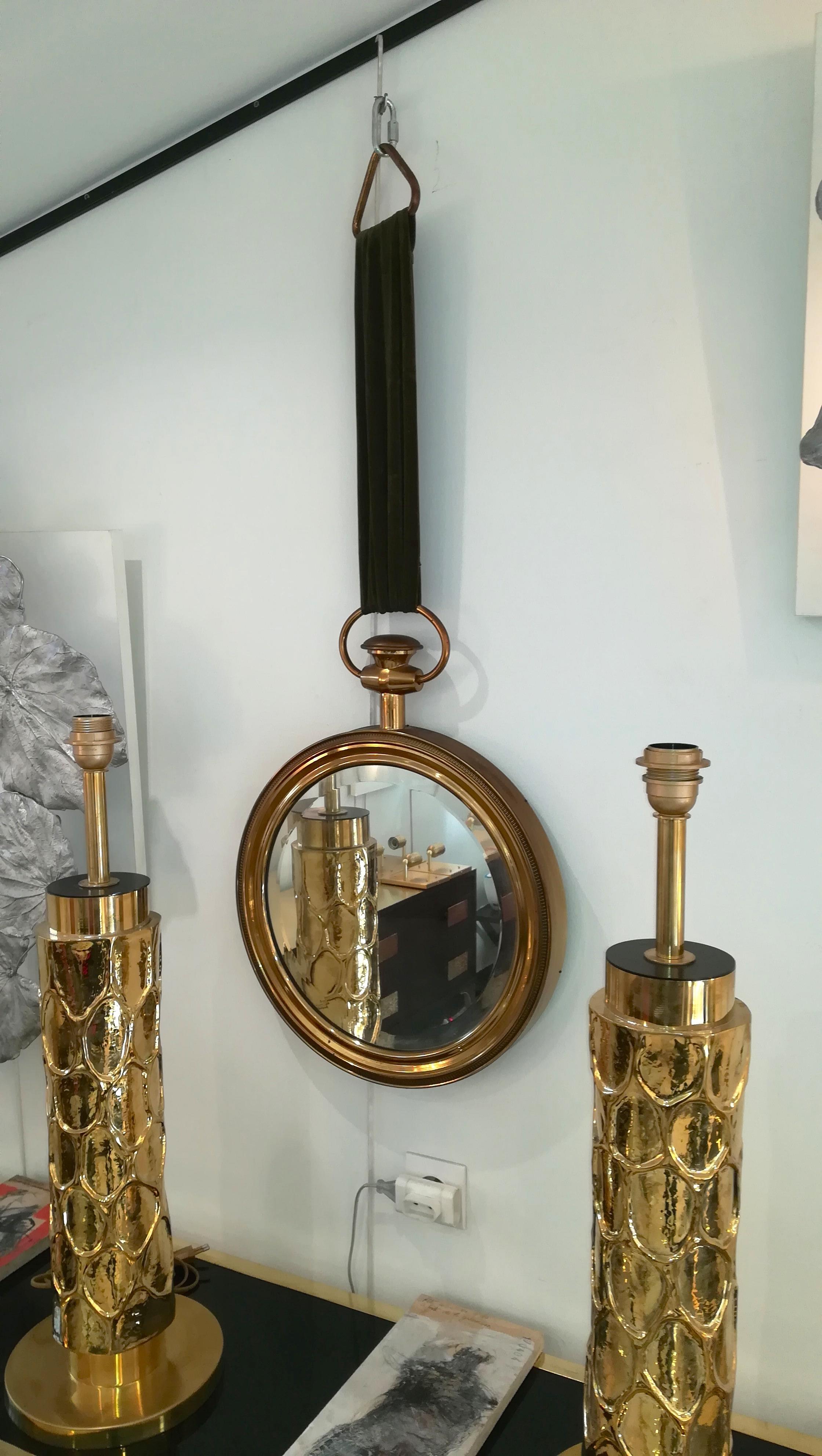 Round wall mirror by Piero Fornasetti in a profiled brass frame
(looking like a pocket watch). The mirror is bevelled all around
The mirror hangs down from a green velvet ribbon with a brass triangle.
Very good condition.