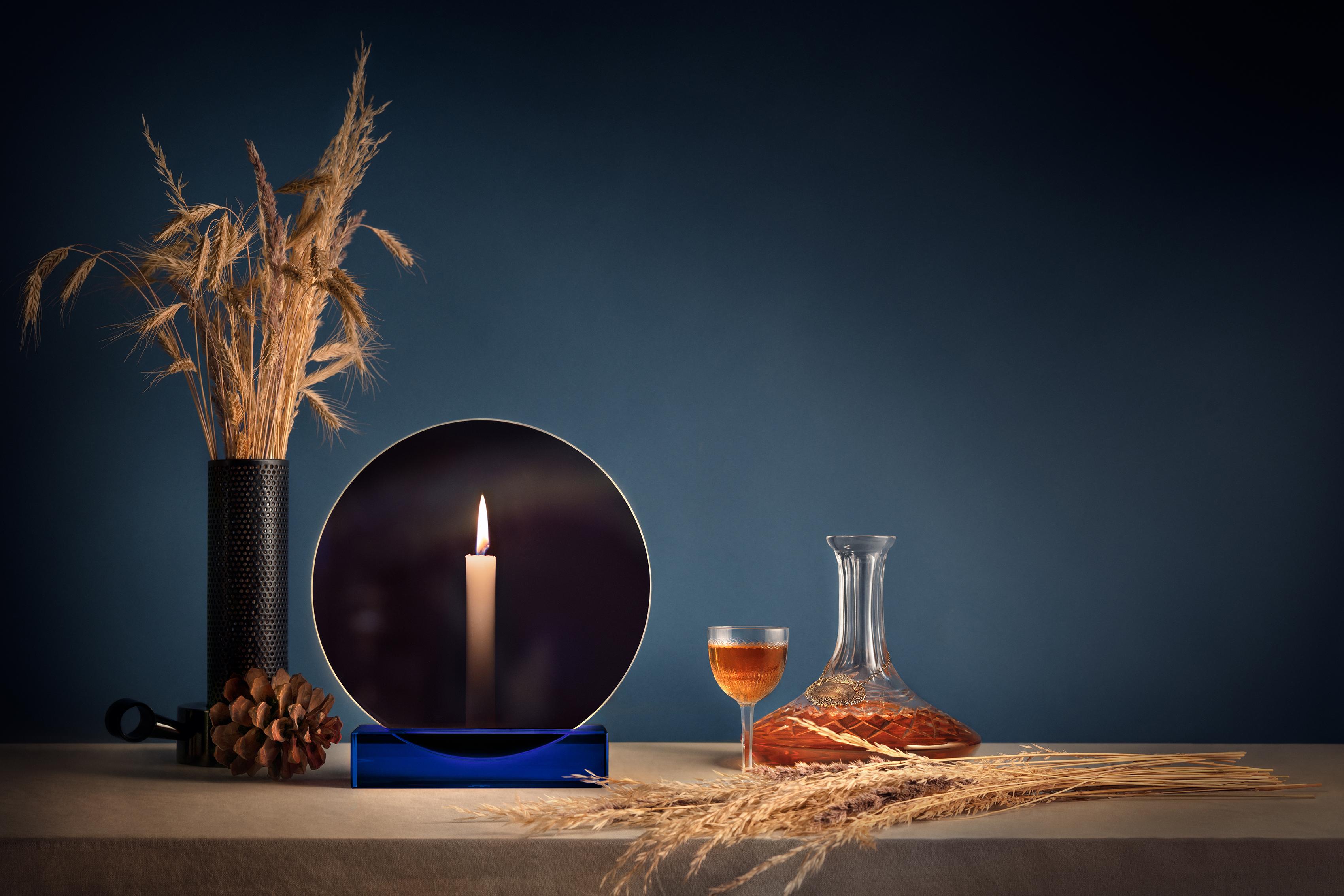 The two-sided Spegla is an interior object that works both as a mirror and a candle holder. The circular glass sheet reflects the light of the room when the candle isn’t lit. While the candle is burning, the glass sheet transmits the light through