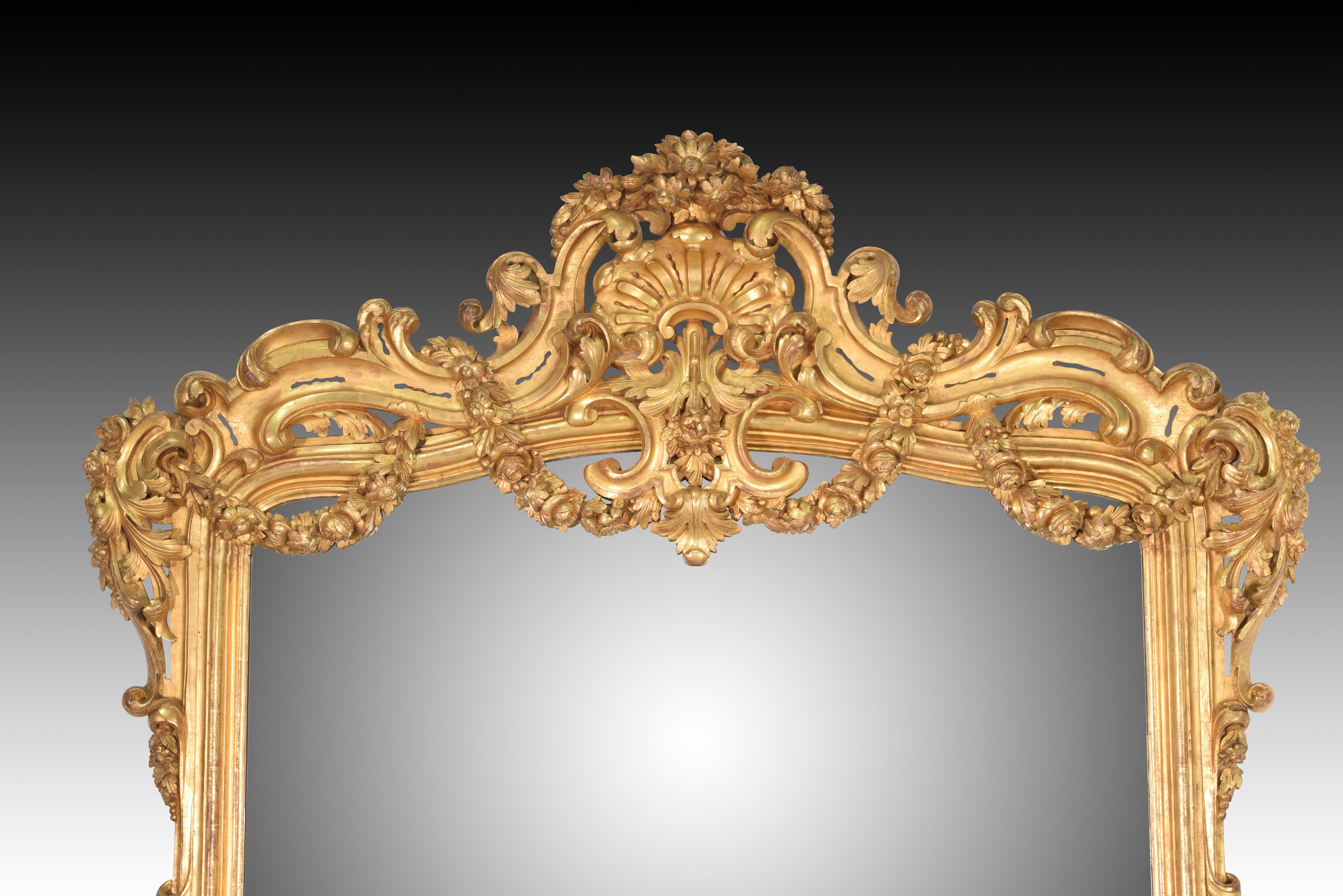 Mirror. Carved and gilded wood. Spain, 19th century.

 Rectangular wall mirror with a frame made of carved and gilded wood, with some openwork areas. It has a crest at the top, with architectural and vegetal decoration (garlands of flowers,