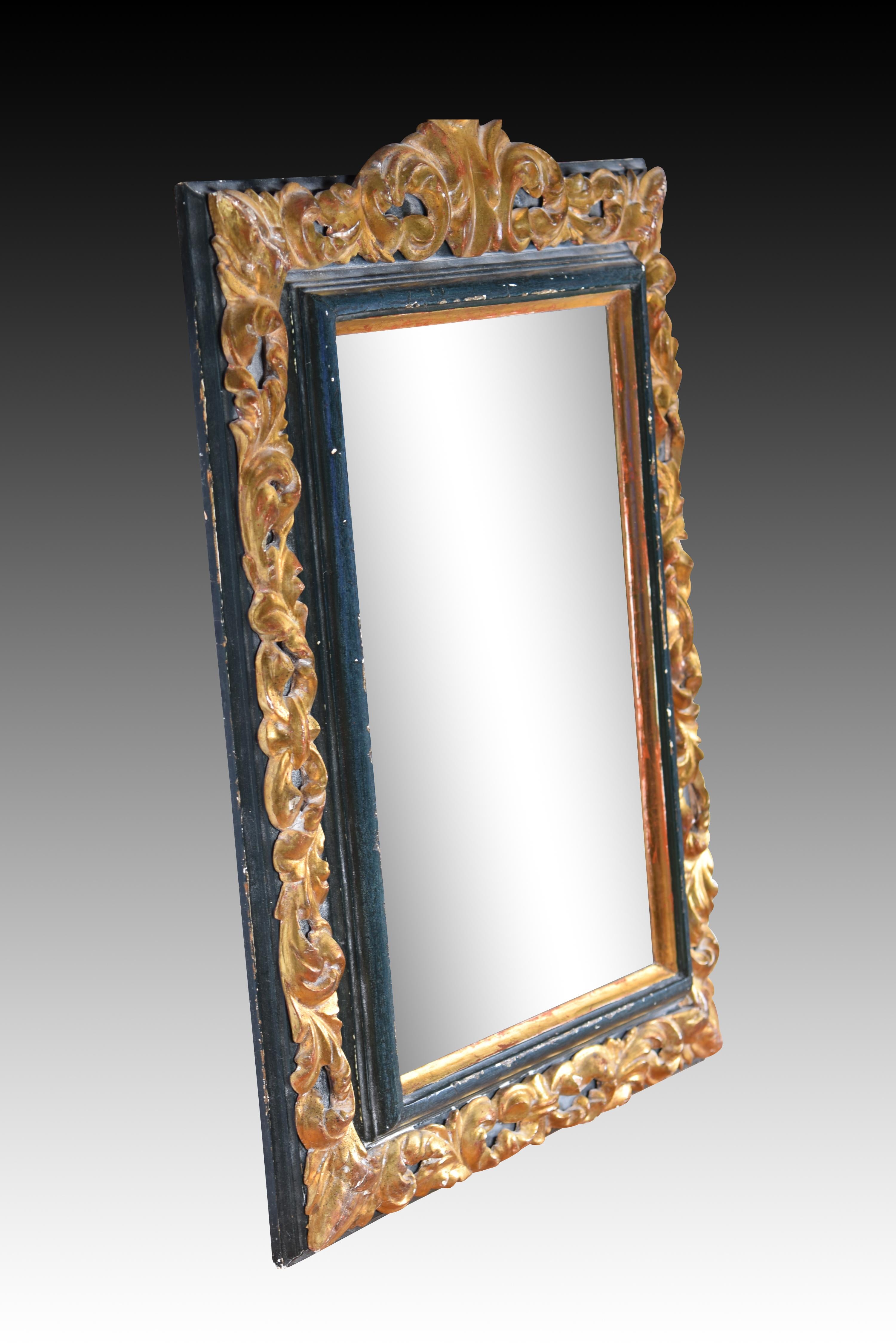 Mirror. Carved and polychrome wood. Spanish school, 20th century, following ancient models. 
Rectangular wall mirror made of wood and decorated with a composition based on plant elements in relief on the front, with a small crest on the top.