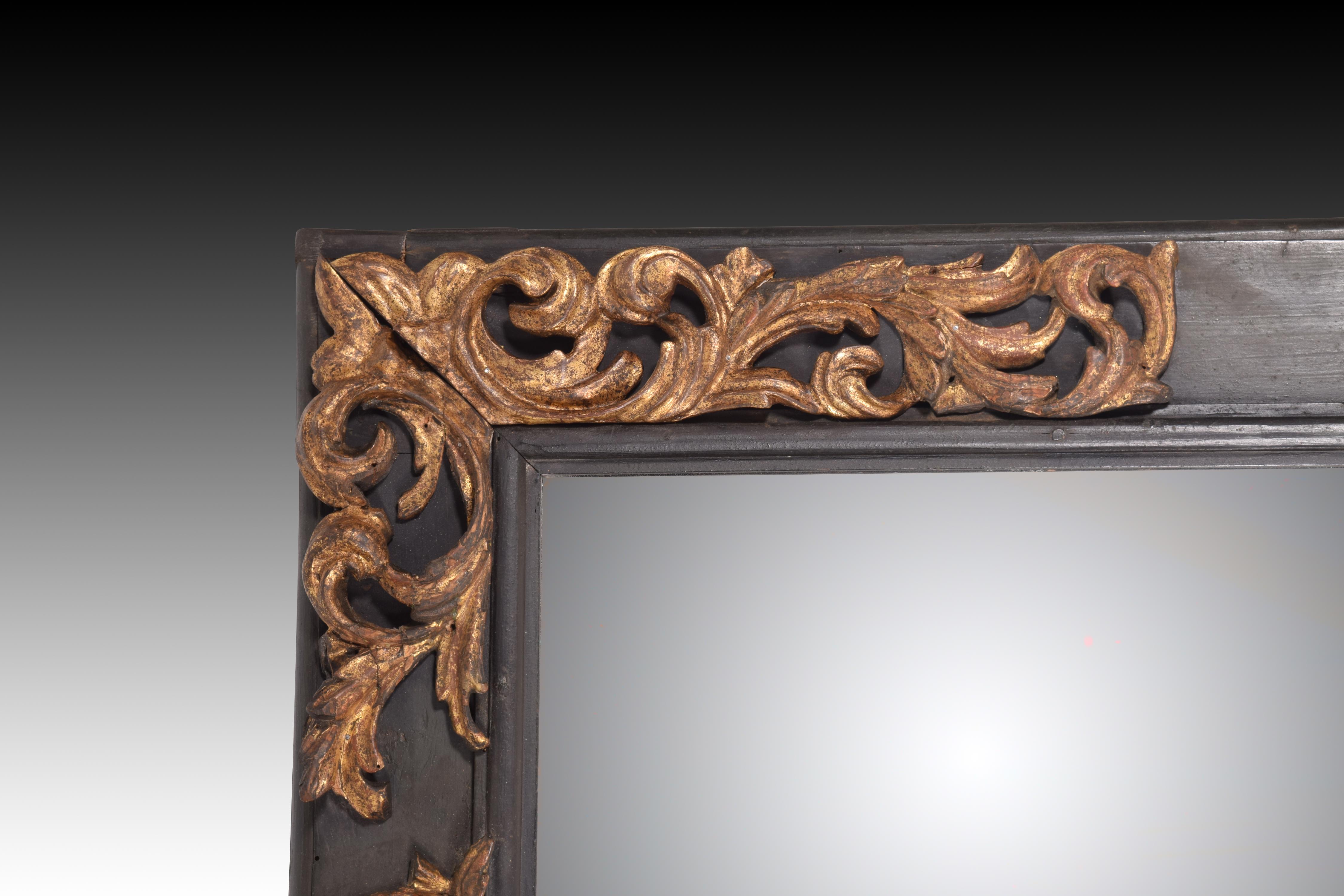 Mirror. Carved wood. XVII century. 
Mirror with a slightly rectangular carved wooden frame that has a metal piece on one of its smaller sides so it can be hung on the wall. The frame has been decorated with a composition based on somewhat fleshy