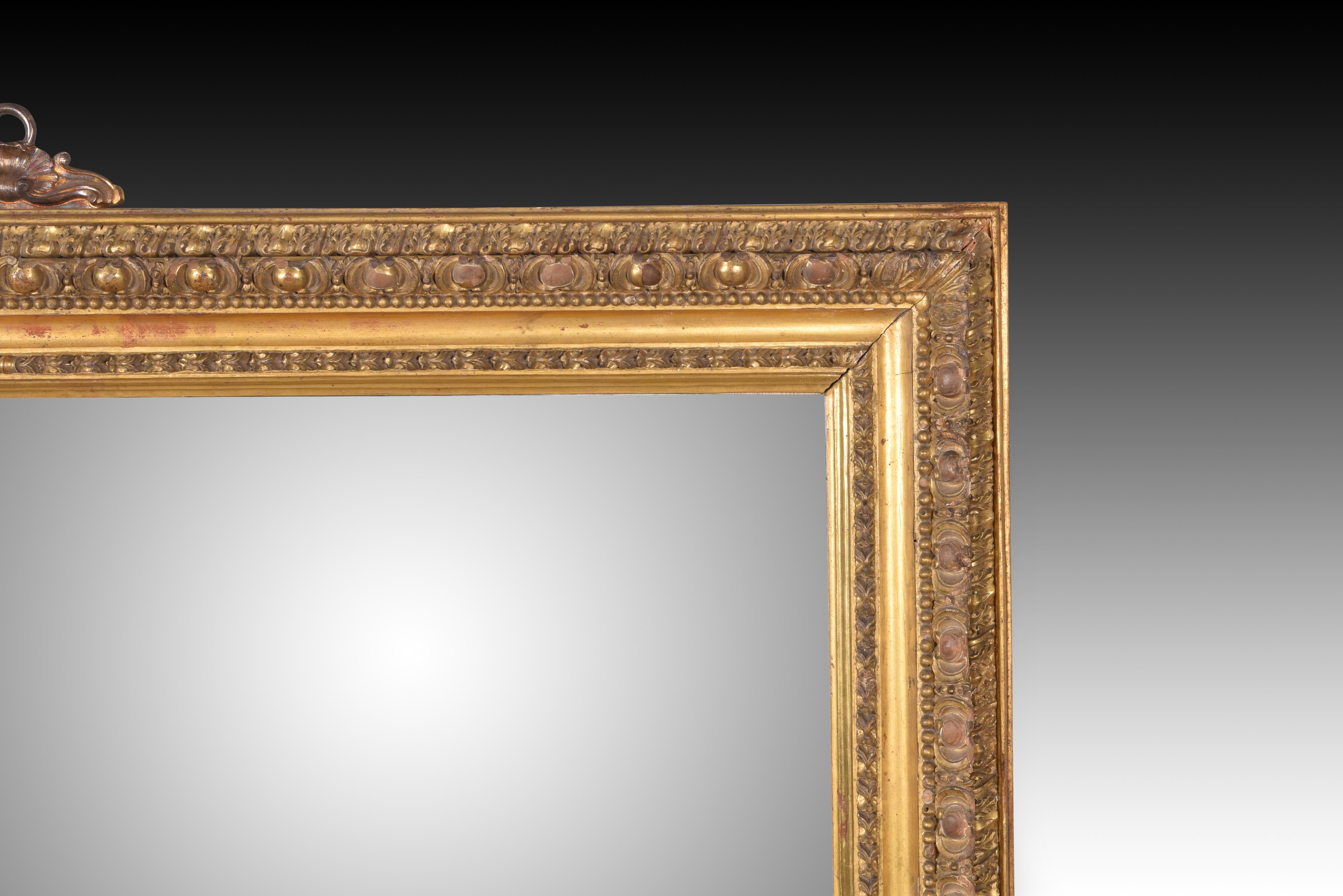 Mirror. Carved wood. 20th century, following 19th century models. 
Wall mirror with decorative elements inside and outside the glass space, finished with a cape. All these decorative details, as well as the shape, are inspired by 19th century models