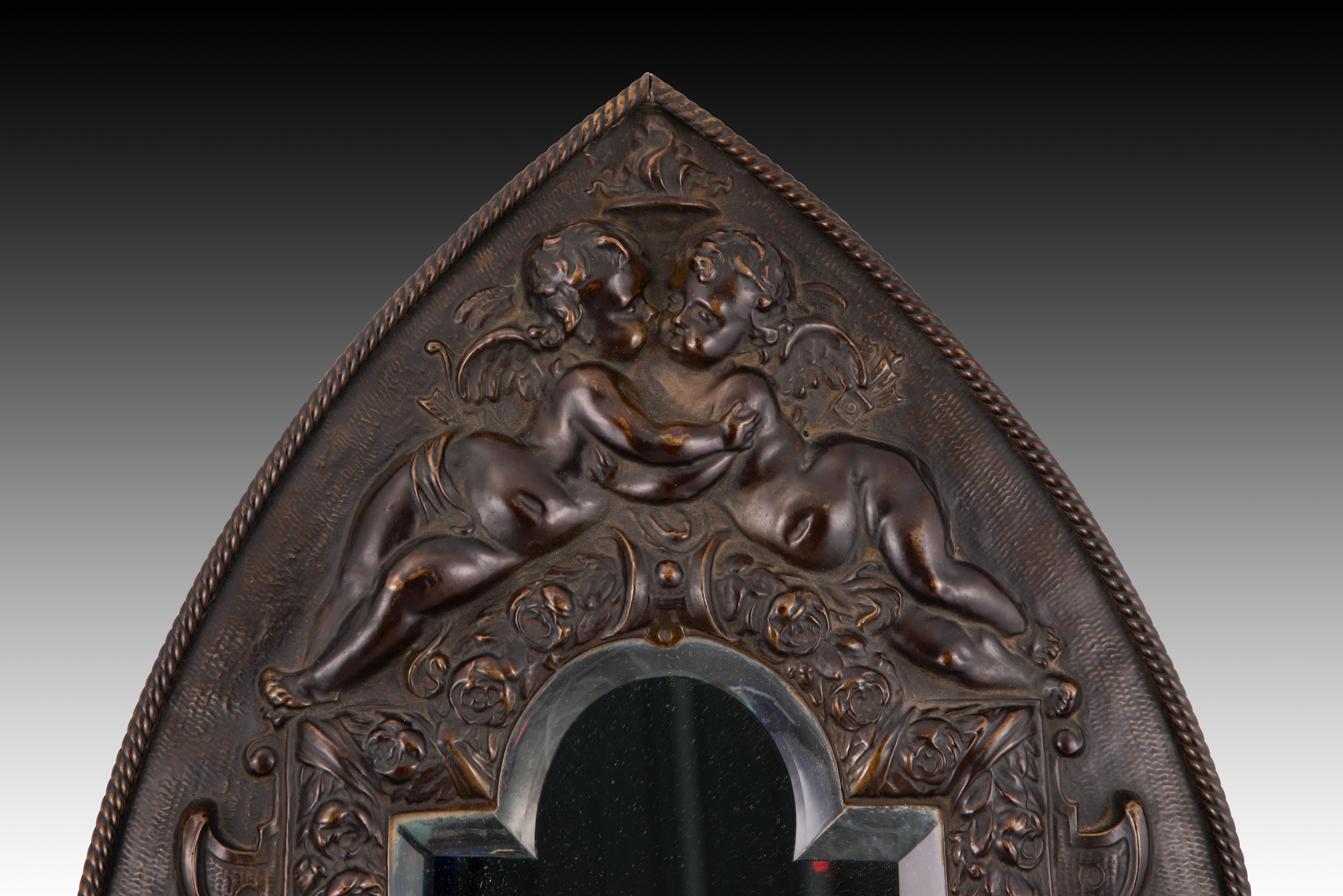 Miroir. Métal gaufré, verre. XIXe siècle. 
Signé. 
Miroir mural avec un cadre en métal repoussé décoré d'une composition architecturale d'un goût classiciste marqué et de souvenirs italiens flanqués, en haut, de deux putti enlacés, et de deux