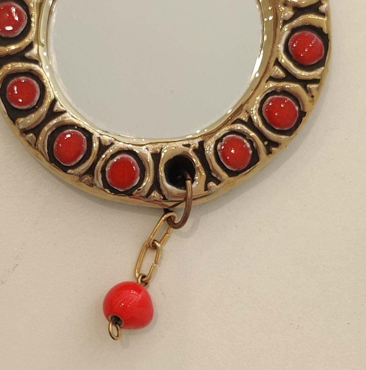 To embellish women's everyday lives, the French ceramist imagines rare objects such as this small-format mirror, ideal for carrying in your handbag. A red ceramic pearl hangs from the frame, which is decorated with geometric motifs in red enamel and