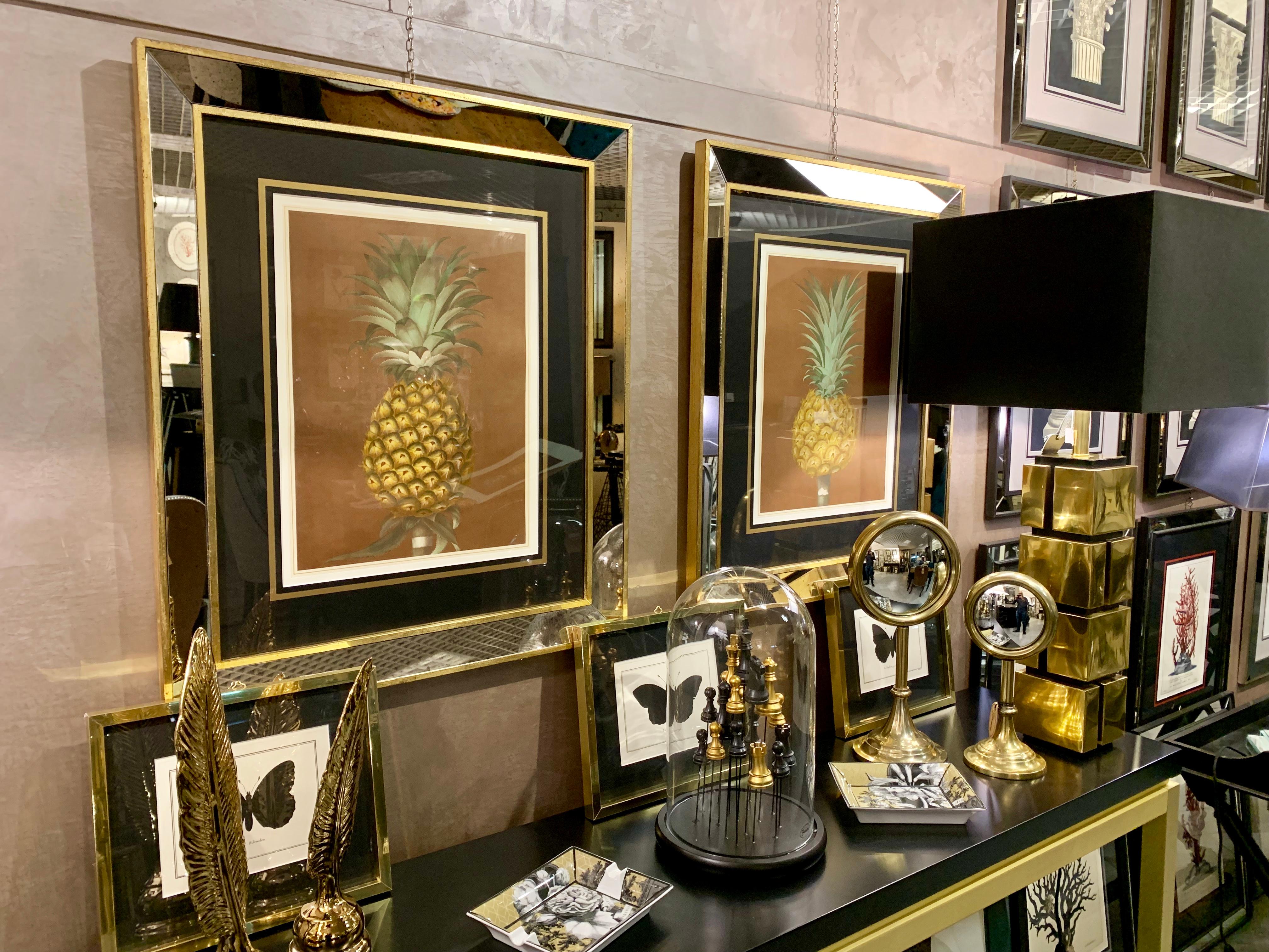 Hand-coloured print entirely made in Florence, Italy by master craftsmen using an antique press and artisanal paper and showing a pineapple. The stylish black mat has gold detailing. Frame made with antique mirror inserts and gold leaf border. Two