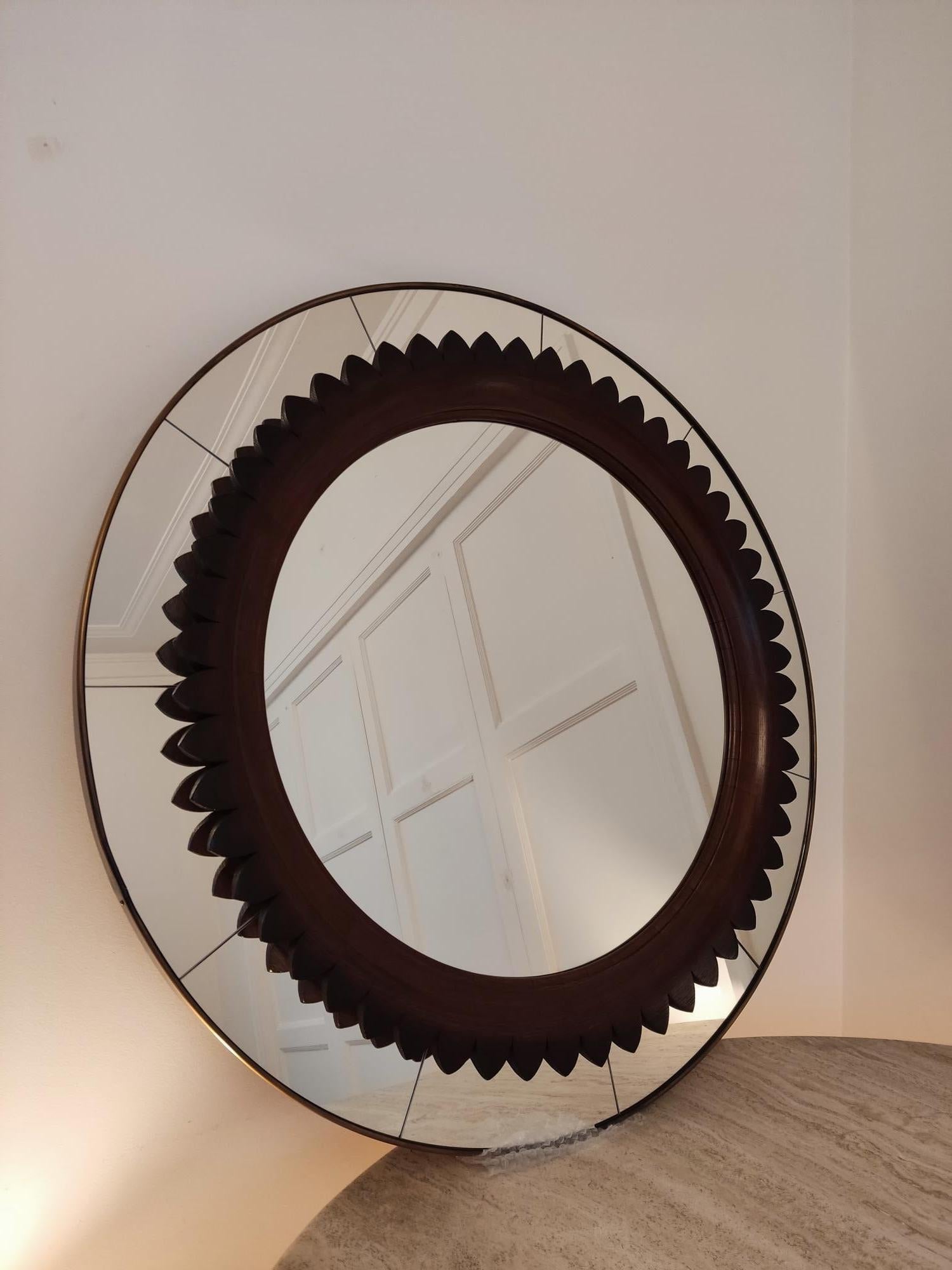 Magnificent Italian wall mirror designed in the 60s by Fratelli Marelli. This mirror has the particularity of having a double frame, the outermost is made of brass. The second has wonderful details, including the scalloped walnut interior circular