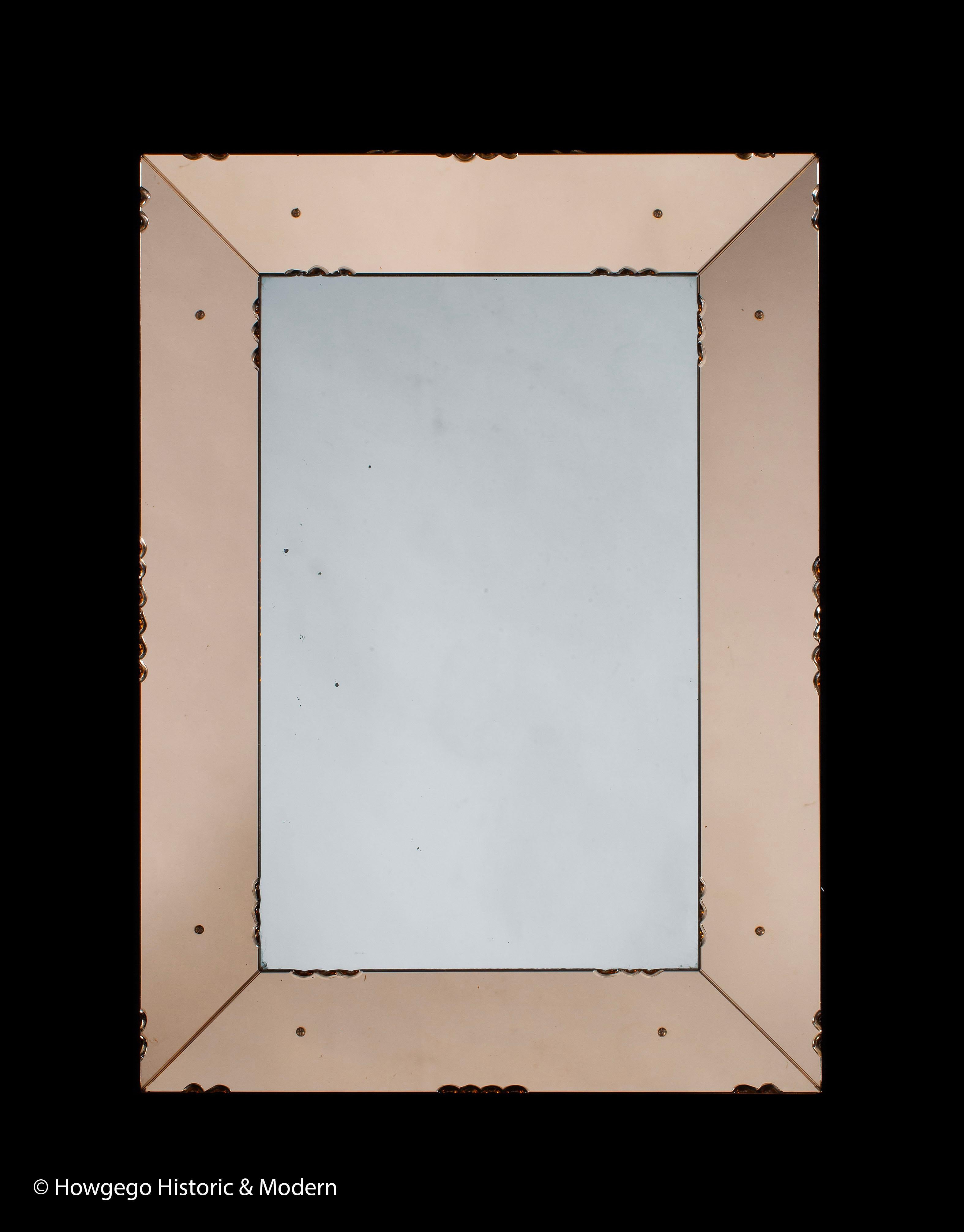 Pretty mirror with canted, border glass simulating a frame which is, unusually, orange tinted reflecting the fashion of the time
The canted border reflects different objects and light from 360 around the mirror
Lovely detailing - scalloped in the